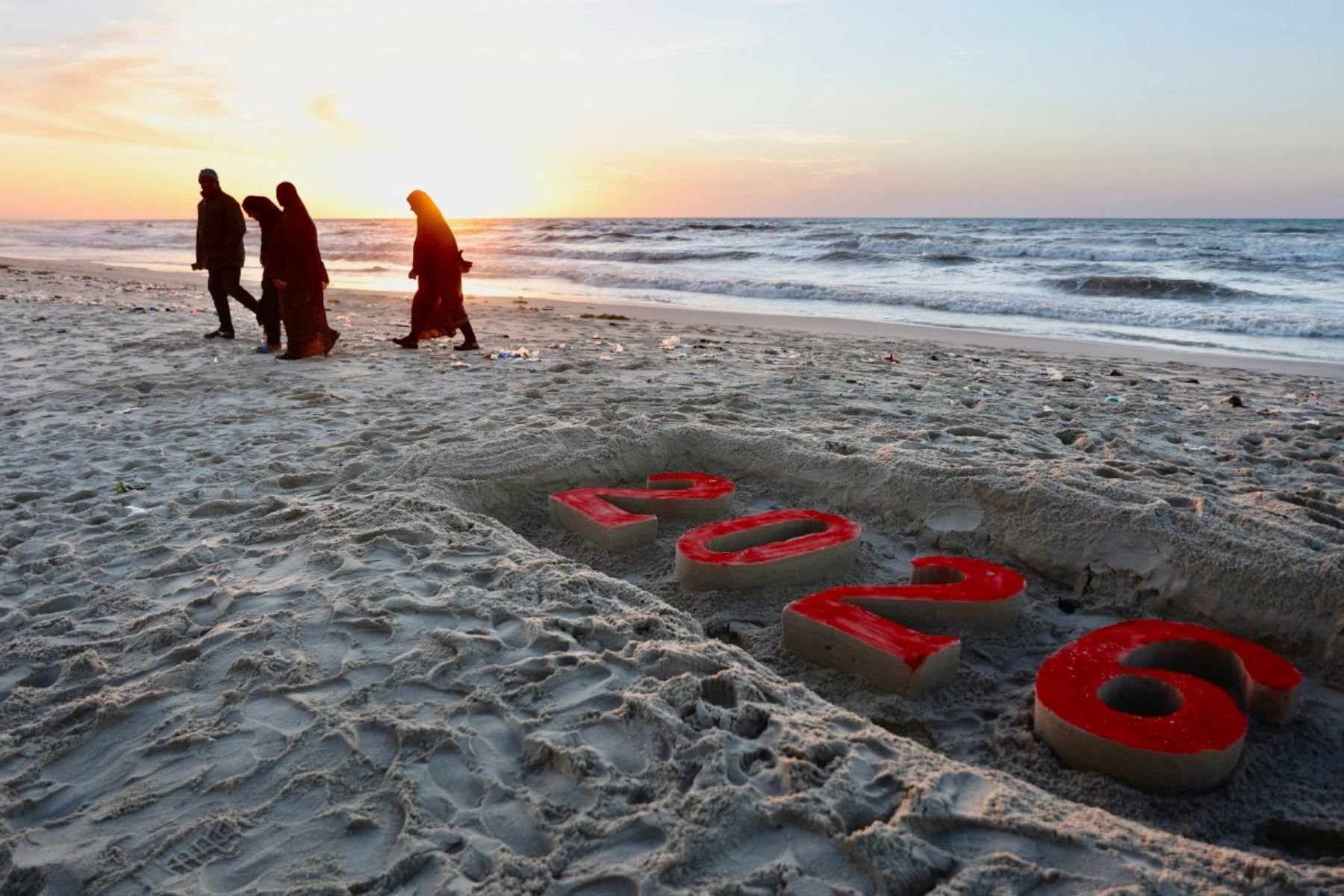 Artistas locales encontraron en la arena y en telas improvisadas una forma de expresar el tránsito hacia 2026. Estos gestos simbólicos surgieron como una necesidad de afirmar la existencia, aun cuando el entorno físico reflejaba destrucción, cansancio y una profunda huella emocional tras meses de conflicto. Foto: AFP