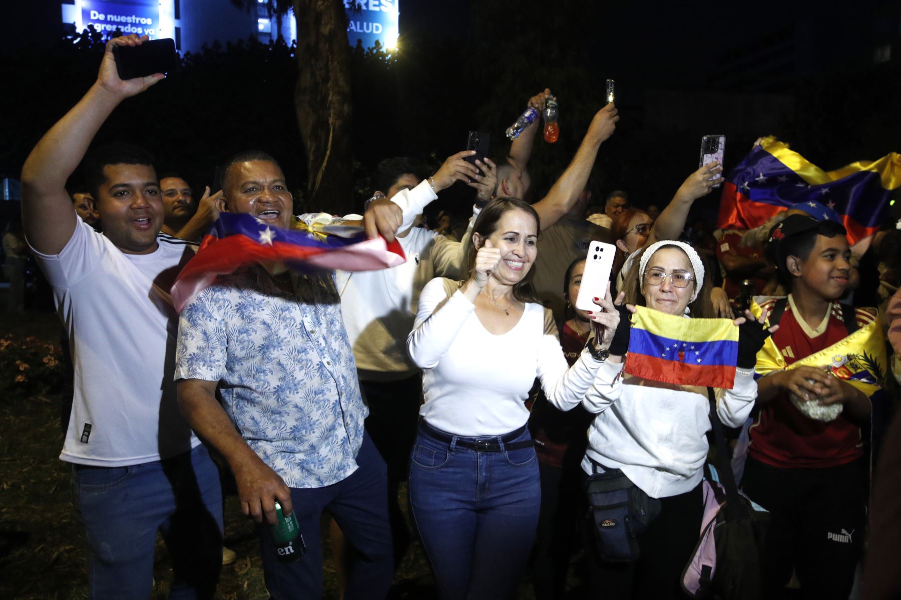 Durante la concentración, familias completas se reunieron en espacios públicos de Lima, muchas con niños, para compartir el momento histórico. Algunos siguieron las noticias en tiempo real desde teléfonos móviles, mientras otros intercambiaban mensajes con familiares en Venezuela, marcados por la emoción y la incertidumbre. 
Foto: ANDINA/Eddy Ramos