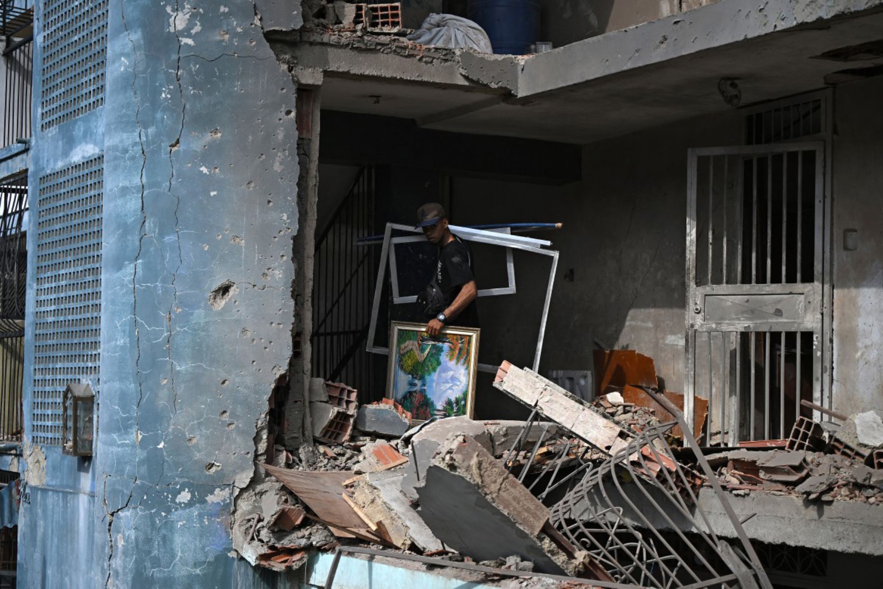 César Díaz , hijo del dueño de un apartamento dañado, es visto durante la limpieza del mismo en Catia La Mar, estado de La Guaira, Venezuela, el 4 de enero de 2026, un día después de que el líder venezolano, Nicolás Maduro, fuera capturado en un ataque estadounidense.
Foto: AFP