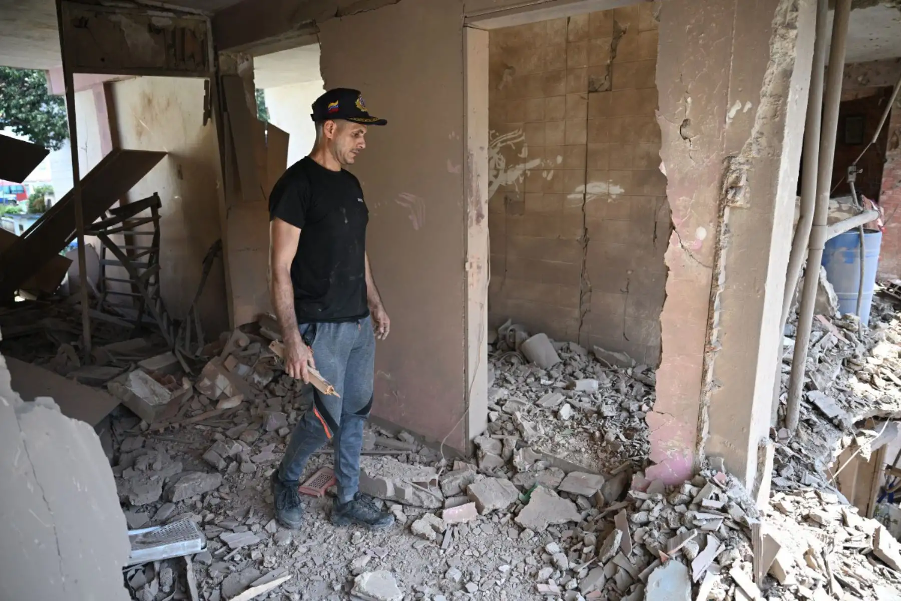 Jesús Linares camina en su apartamento dañado en Catia La Mar, estado de La Guaira, Venezuela, el 4 de enero de 2026, un día después de que el líder de Venezuela, Nicolás Maduro, fuera capturado en un ataque estadounidense.
Foto: AFP