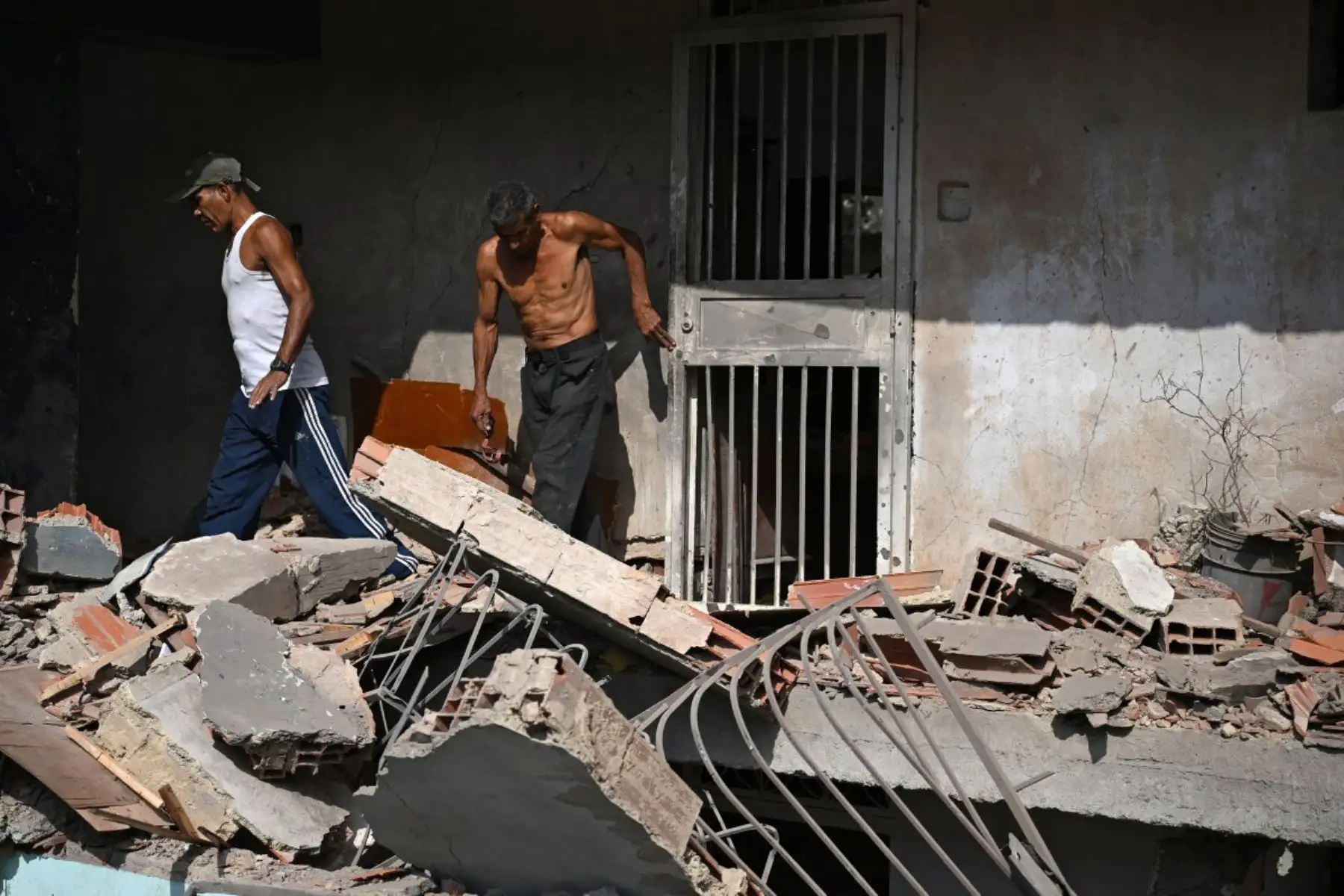 Wilman González, familiar del propietario, ayuda a limpiar un apartamento dañado en Catia La Mar, estado de La Guaira, Venezuela, el 4 de enero de 2026, un día después de que el líder de Venezuela, Nicolás Maduro, fuera capturado en un ataque estadounidense.
Foto: AFP