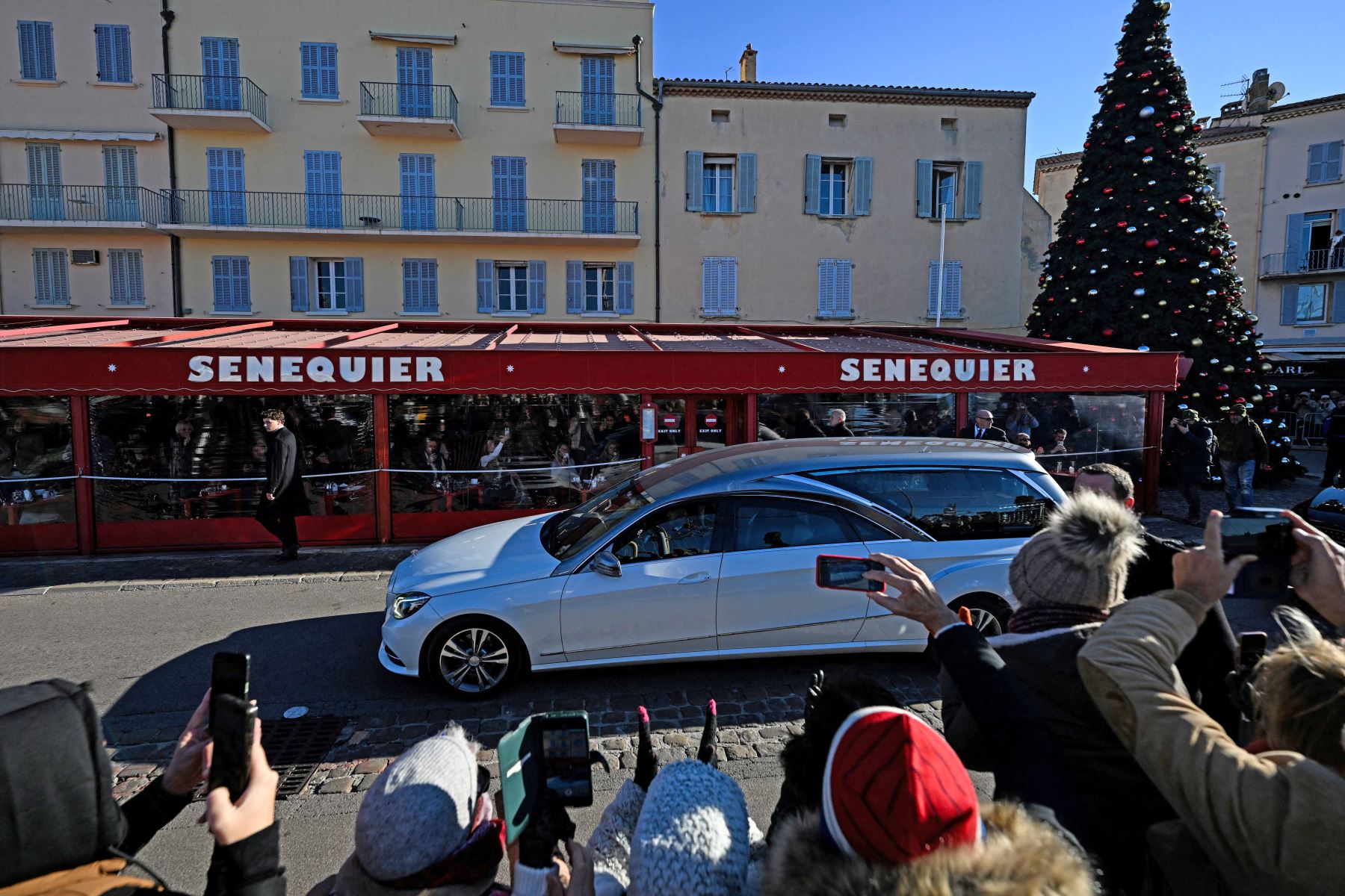 El coche fúnebre que transporta el ataúd pasa por el restaurante cafetería Senequier y se dirige a la iglesia de Notre-Dame de l