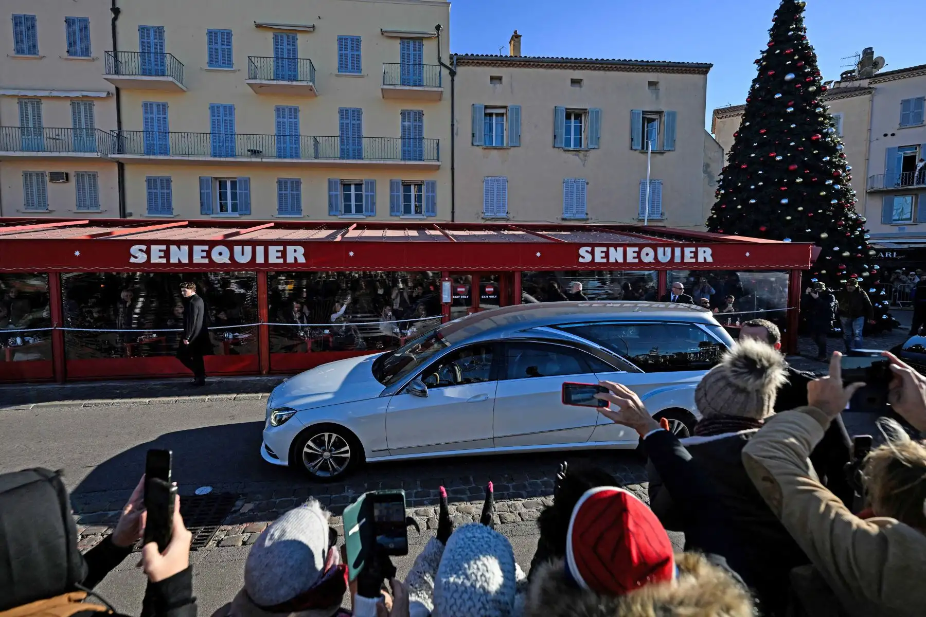 El coche fúnebre que transporta el ataúd pasa por el restaurante cafetería Senequier y se dirige a la iglesia de Notre-Dame de l