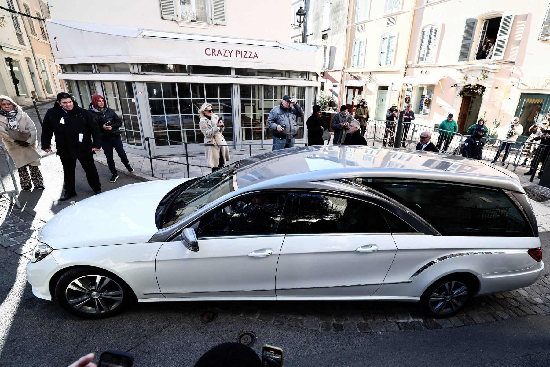 El coche fúnebre que transporta el ataúd pasa por el restaurante cafetería Senequier y se dirige a la iglesia de Notre-Dame de l
