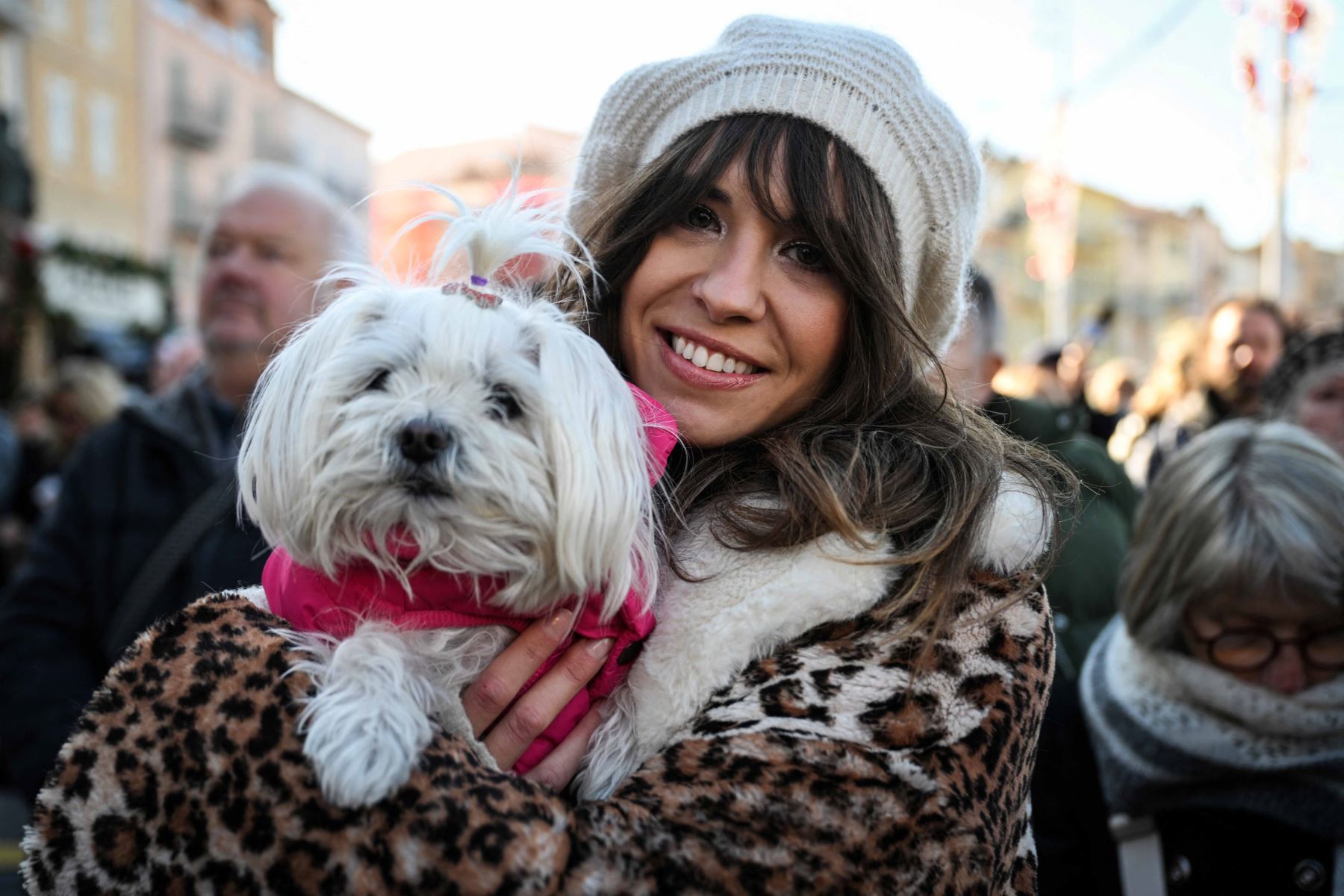 Una fan sostiene a su perro mientras observa en una pantalla la transmisión en vivo del funeral de la fallecida actriz francesa Brigitte Bardot, en la iglesia de Notre-Dame de l