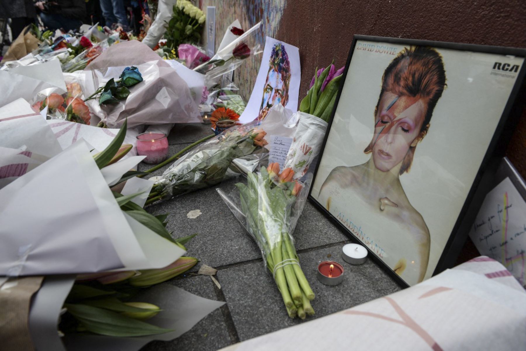 Se ven homenajes debajo de un mural del cantante británico David Bowie, tras el anuncio de la muerte de Bowie, en Brixton, sur de Londres, el 11 de enero de 2016. El icono de la música británica David Bowie murió de cáncer a los 69 años el 10 de enero de 2016, dibujando una efusión de homenajes a la innovadora estrella famosa por éxitos innovadores como "Ziggy Stardust" y su estilo teatral que cambia de forma. (Foto de CHRIS RATCLIFFE / AFP)