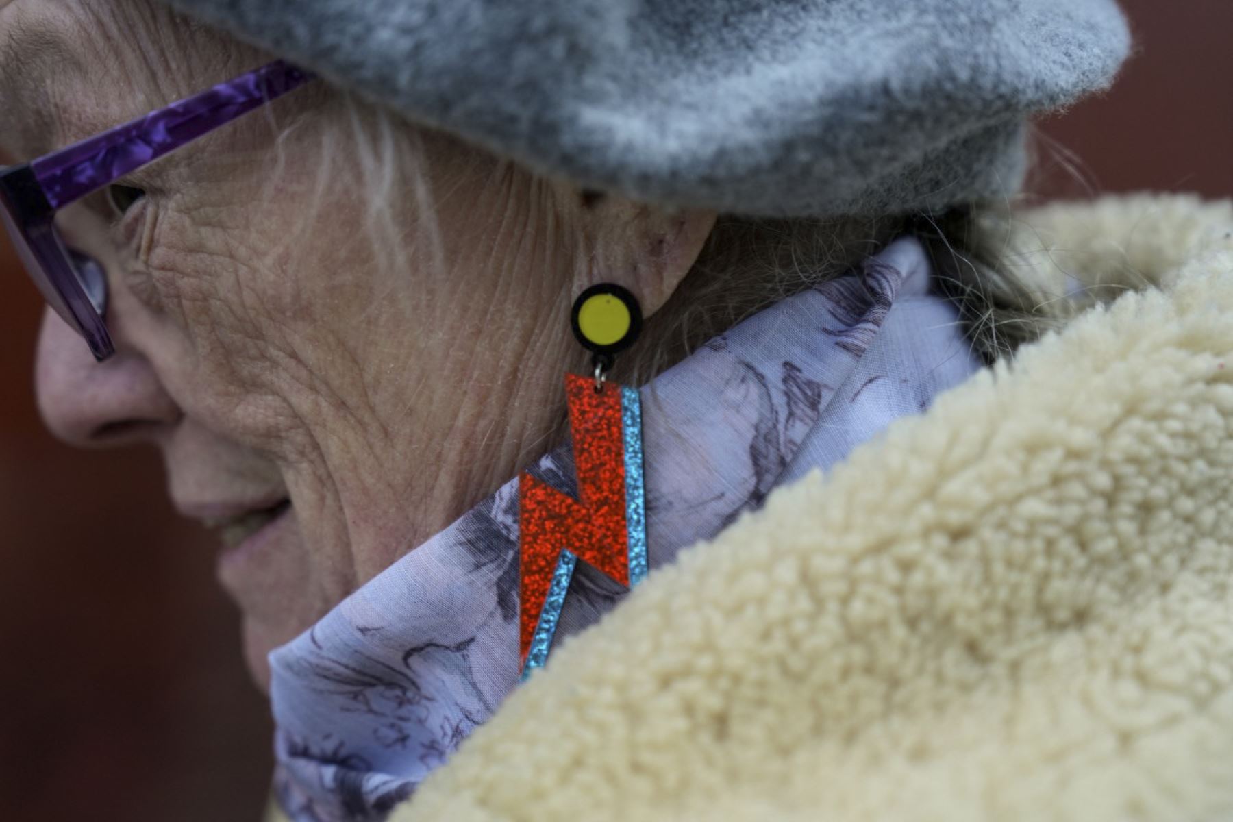Una visitante muestra sus pendientes relámpago durante una visita a un mural del difunto icono del pop británico David Bowie creado por el artista callejero australiano James Cochran, también conocido como Jimmy C, en Brixton, sur de Londres, el 10 de enero de 2026, en el décimo aniversario de la muerte del músico. (Foto de CARLOS JASSO / AFP)