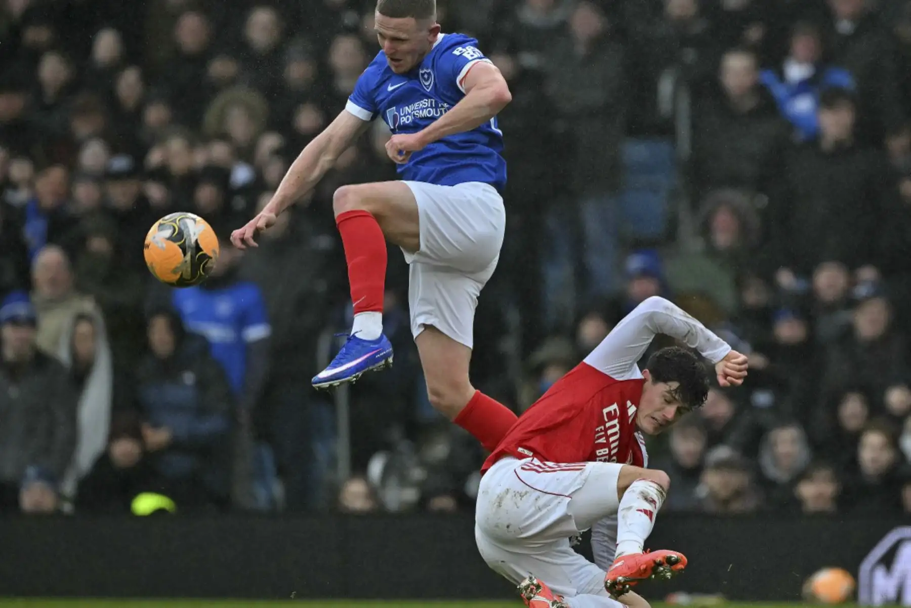 El delantero inglés del Portsmouth #09 Colby Bishop (Izquida) salta por encima del defensor danés del Arsenal #16, Christian Norgaard, para controlar el balón durante el partido de tercera ronda de la Copa FA de Inglaterra entre Portsmouth y Arsenal en Fratton Park en Portsmouth, al sur de Inglaterra, el 11 de enero de 2026. (Foto de Glyn KIRK / AFP)