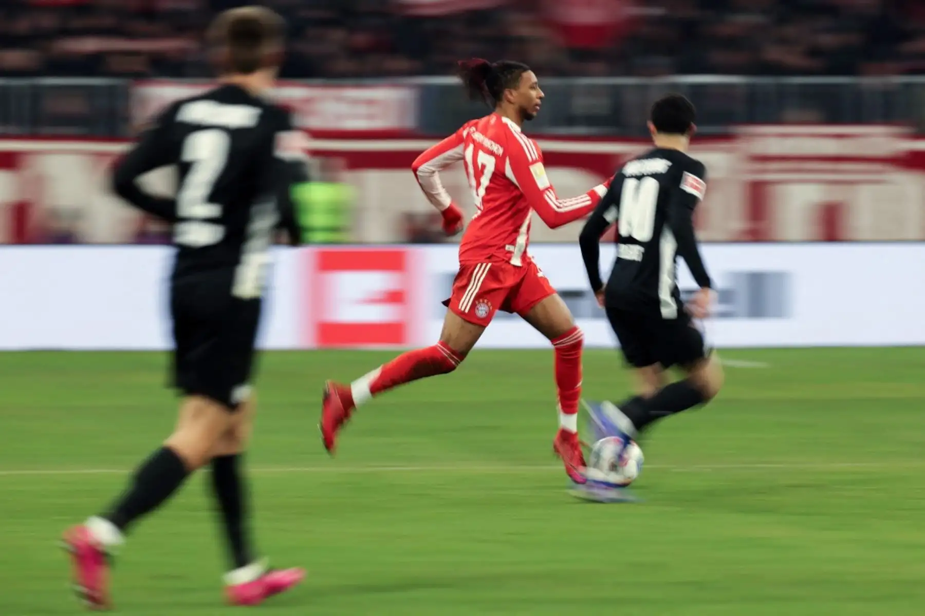 El centrocampista francés del Bayern de Múnich #17 Michael Olise (C) y el centrocampista estadounidense del Wolfsburg #40 Kevin Paredes compiten por el balón durante el partido de fútbol de primera división alemana de la Bundesliga entre el FC Bayern de Múnich y el VfL Wolfsburg en Múnich, sur de Alemania, el 11 de enero de 2026. (Foto de Alexandra BEIER / AFP)