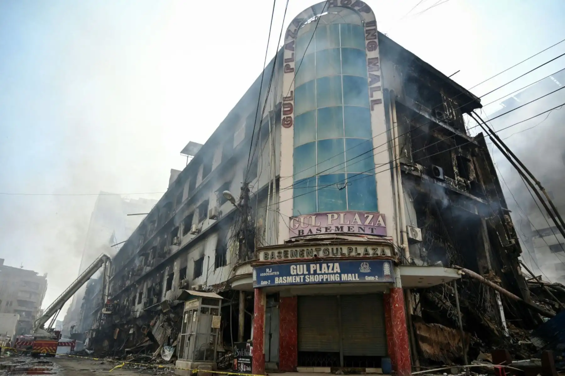 Bomberos y rescatistas realizan una operación de enfriamiento entre los escombros tras un gran incendio en un centro comercial de Karachi el 19 de enero de 2026. Foto: ANDINA/AFP