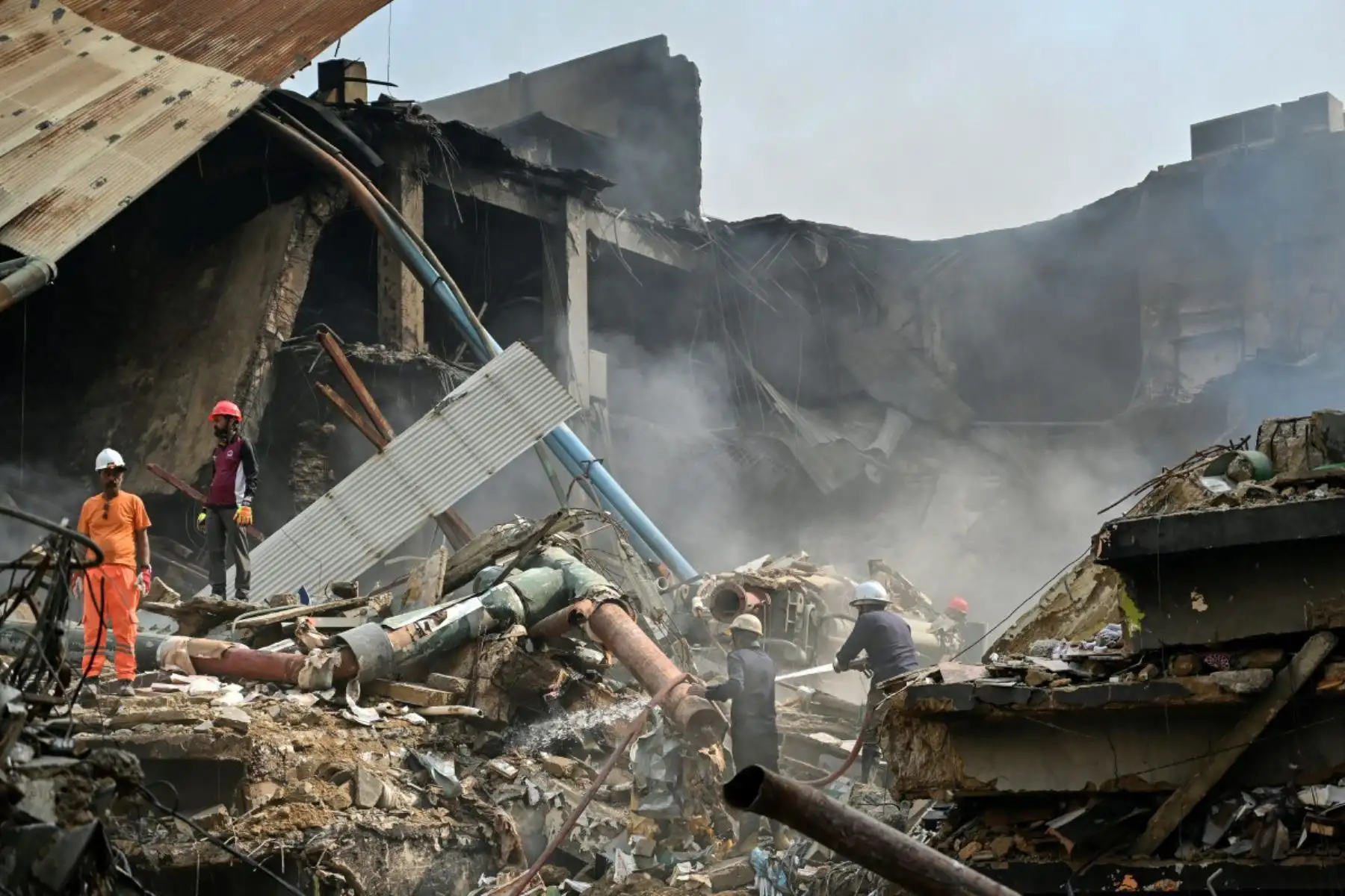 Bomberos y rescatistas realizan una operación de enfriamiento entre los escombros tras un gran incendio en un centro comercial de Karachi el 19 de enero de 2026. Foto: ANDINA/AFP
