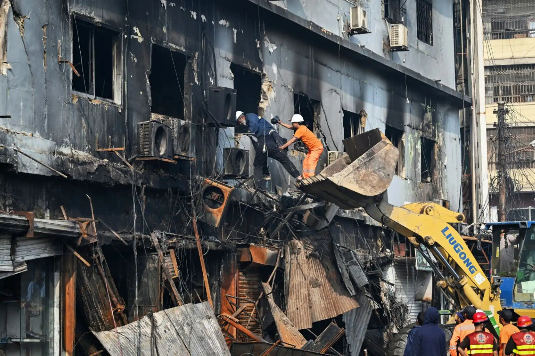 Rescatistas buscan en una estructura quemada tras un gran incendio en un centro comercial de Karachi el 19 de enero de 2026. Foto: ANDINA/AFP