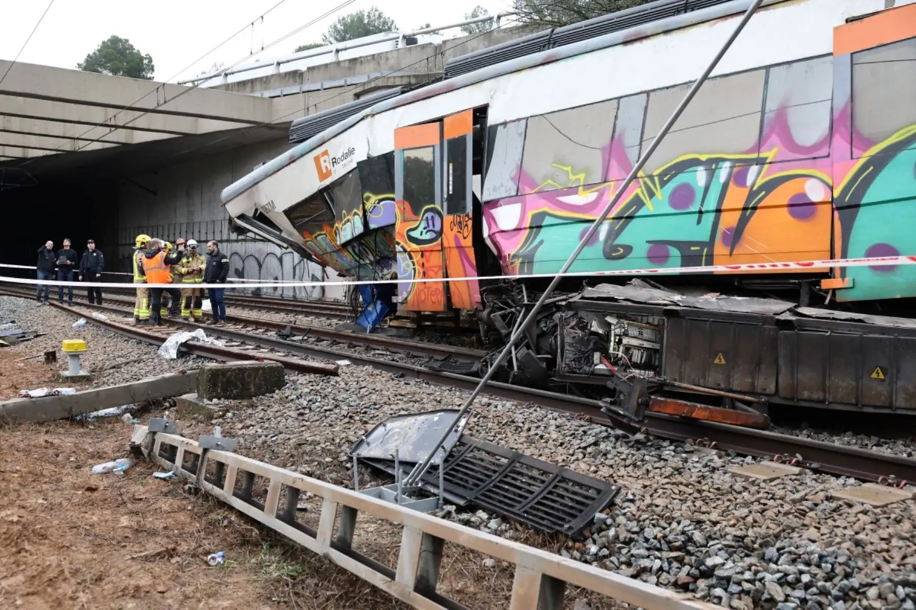 Bomberos trabajan junto a la locomotora en el lugar donde al menos una persona murió y cinco resultaron gravemente heridas al colisionar un tren regional contra un muro entre Sant Sadurní d