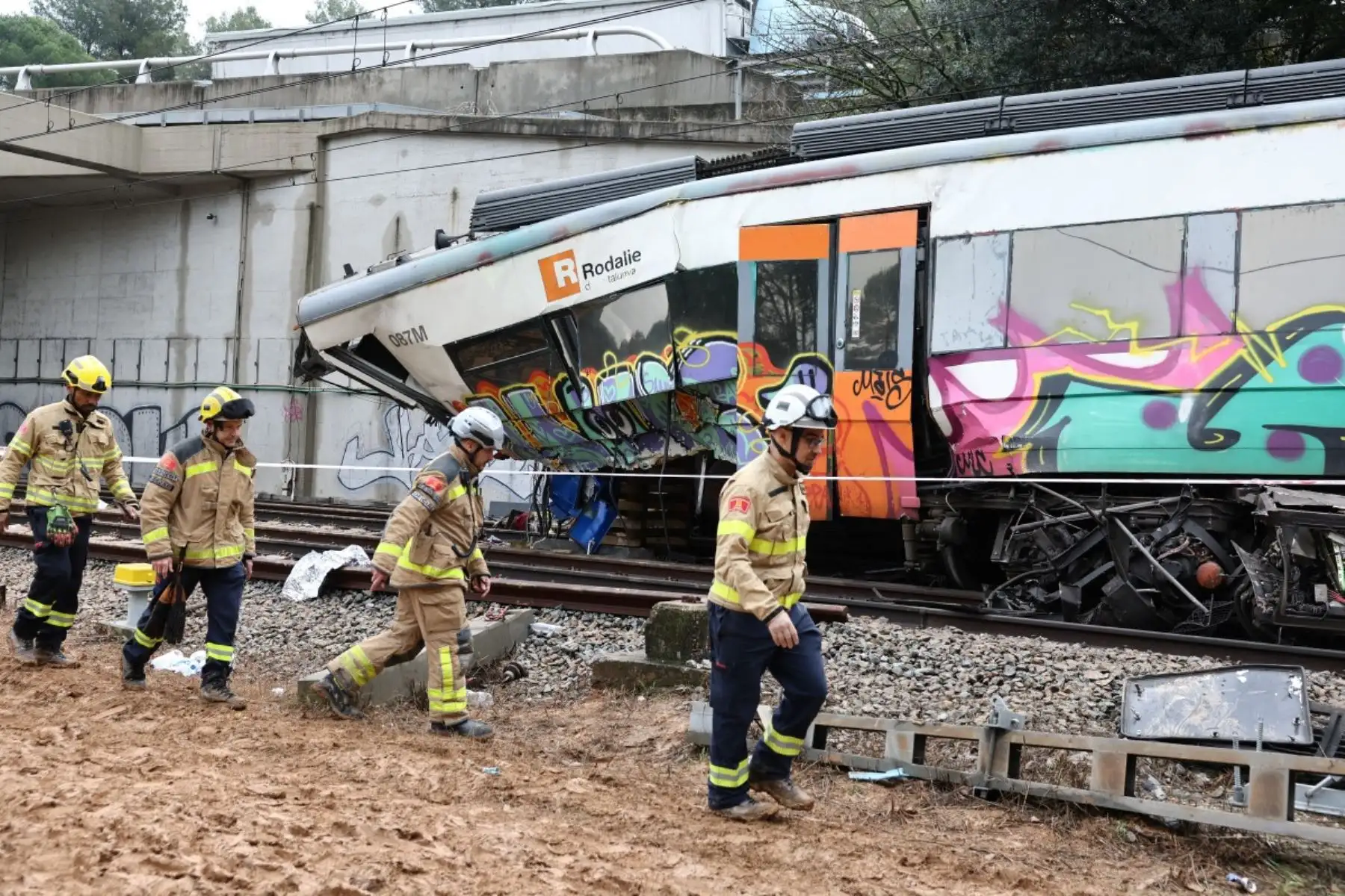 Bomberos trabajan junto a la locomotora en el lugar donde al menos una persona murió y cinco resultaron gravemente heridas al colisionar un tren regional contra un muro entre Sant Sadurní d