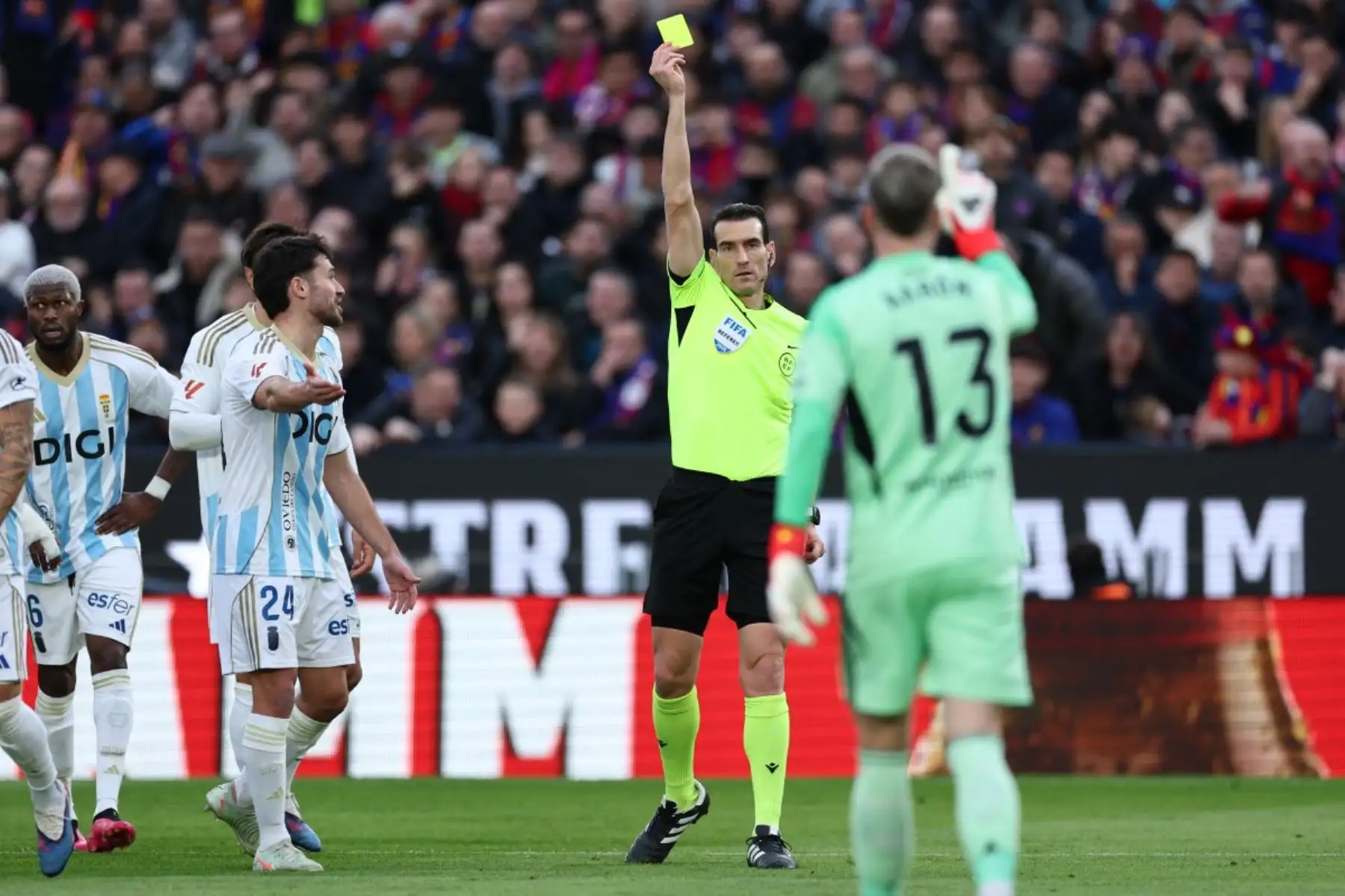 El árbitro español Juan Martínez presenta una tarjeta amarilla al portero español #13 del Real Oviedo, Aaron Escandell Banacloche, durante el partido de fútbol de la liga española entre el FC Barcelona y el Real Oviedo en el Estadio Camp Nou de Barcelona el 25 de enero de 2026. (Foto de Josep LAGO / AFP)