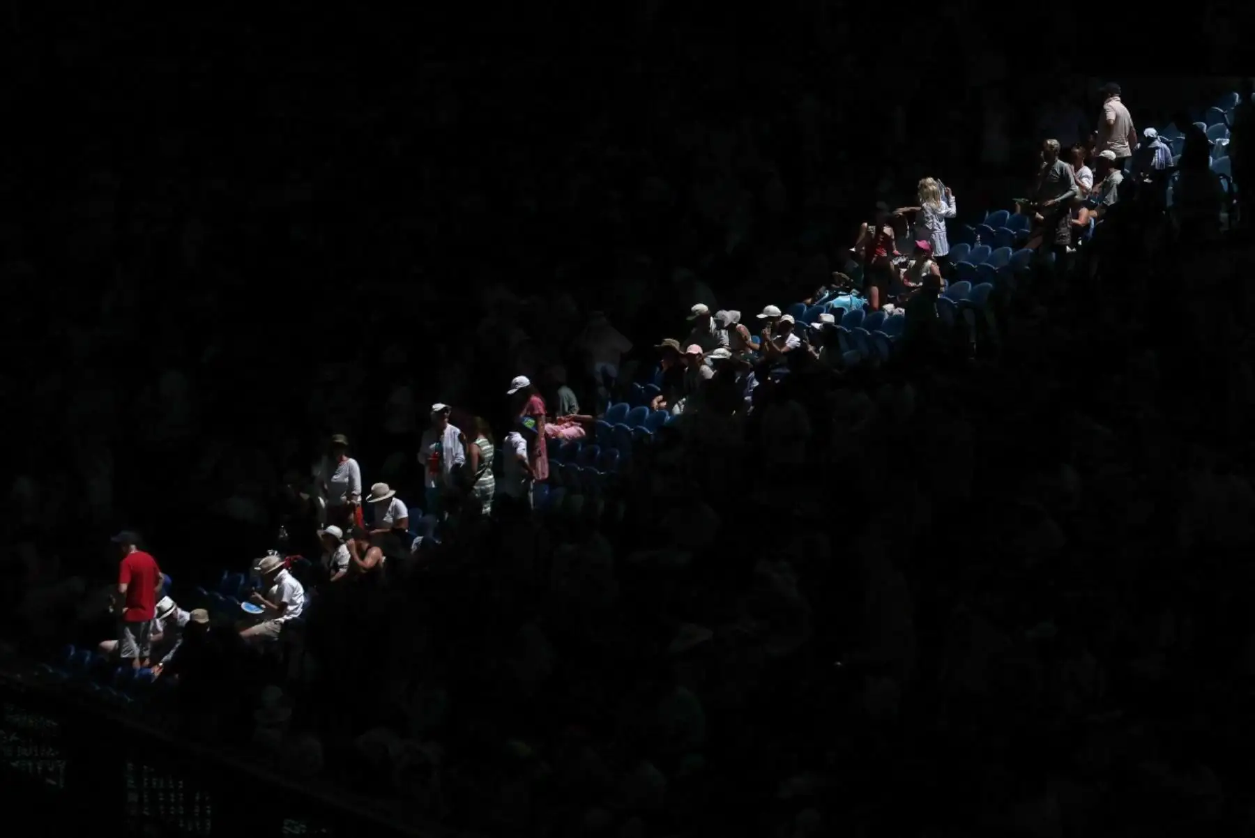 Los espectadores toman fotos durante el cierre del techo del Rod Laver Arena en medio de un calor extremo en el partido individual masculino entre el italiano Jannik Sinner y el estadounidense Eliot Spizzirri en el séptimo día del torneo de tenis del Abierto de Australia en Melbourne el 24 de enero de 2026. (Foto de Martin KEEP / AFP)