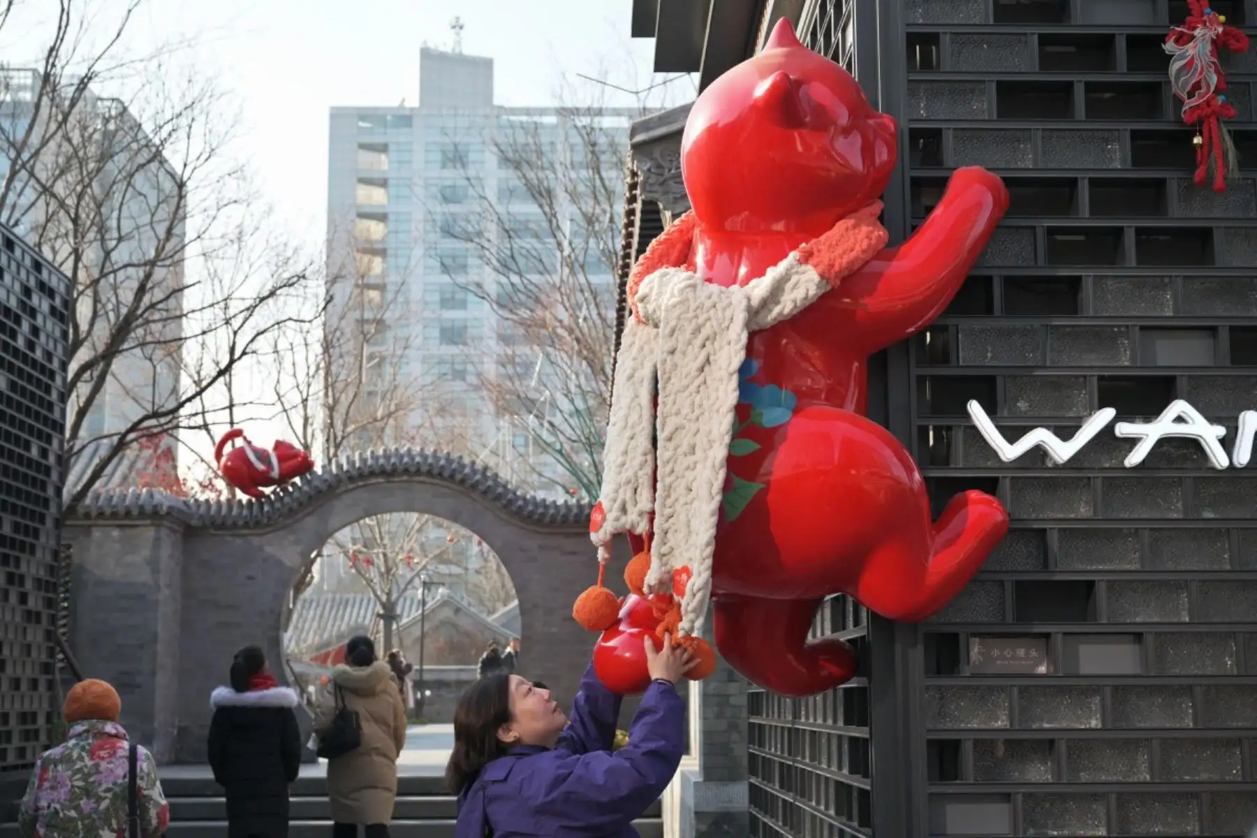 Una mujer toca una instalación de un gato trepando un muro en el centro comercial Zhonghai Daji Alley, en Pekín. Foto: AFP