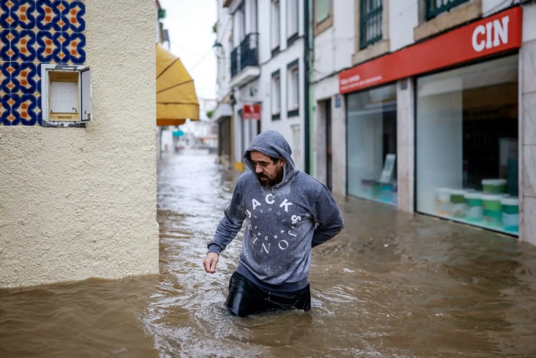 Un hombre camina mientras las aguas del río Sado cubren la calle en Alcácer do Sal, al sur de Portugal, durante la tormenta Leonardo. AFP