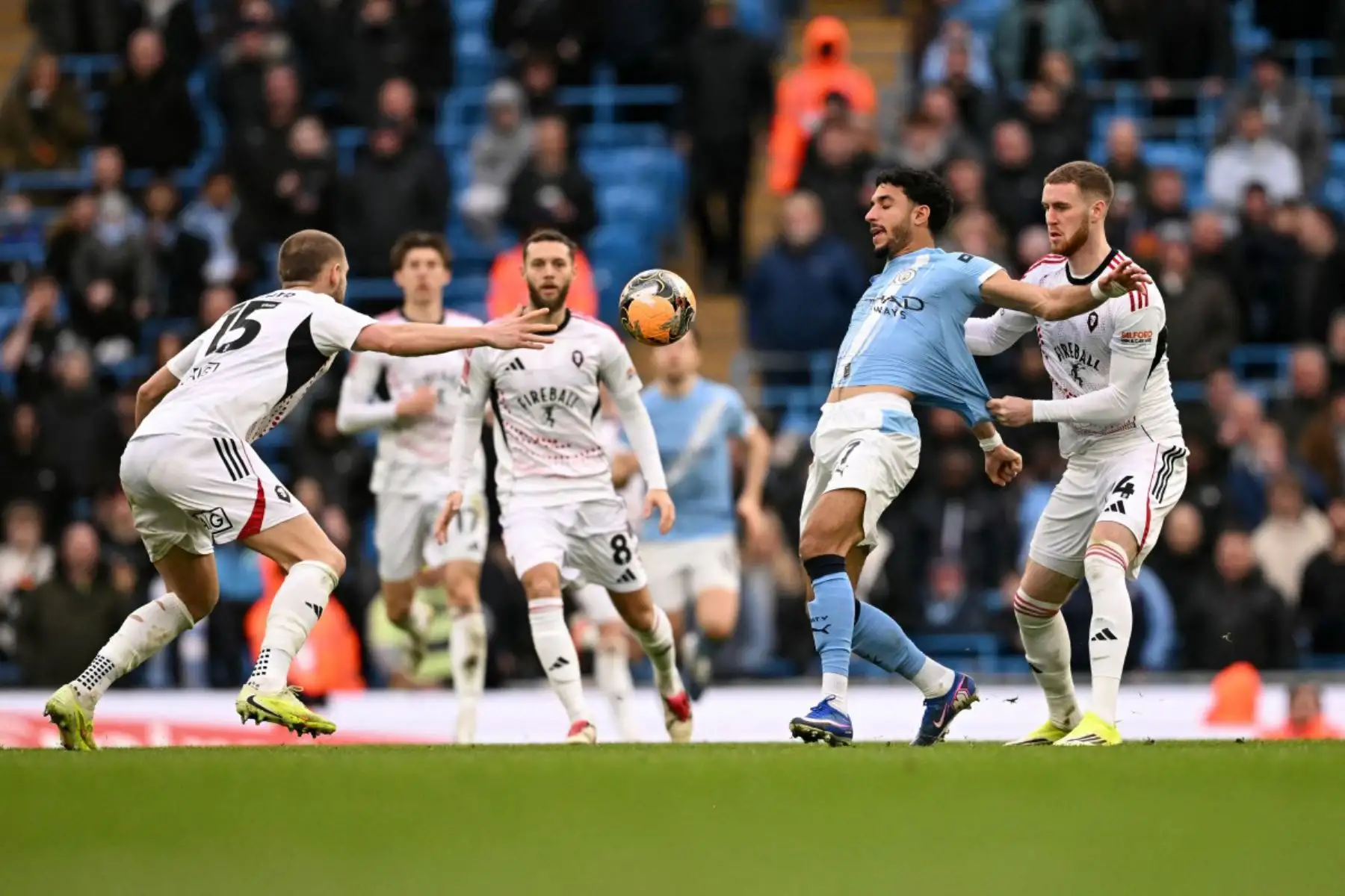 Español El defensa irlandés 24 del Salford City, Todin Olopade, le quita la camiseta al delantero egipcio 07 del Manchester City, Omar Marmoush, durante el partido de tercera ronda de la FA Cup inglesa entre el Manchester City y el Salford City en el Etihad Stadium en Manchester, noroeste de Inglaterra. Foto: ANDINA/AFP