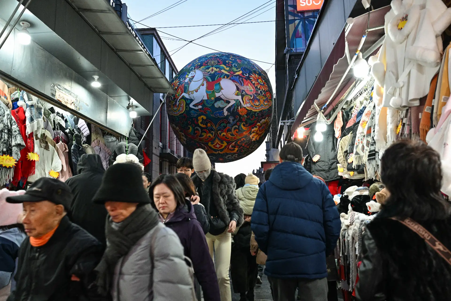 Personas pasean por un mercado decorado con caballos en Pekín, antes del Año Nuevo Lunar del Caballo. 
Foto: AFP