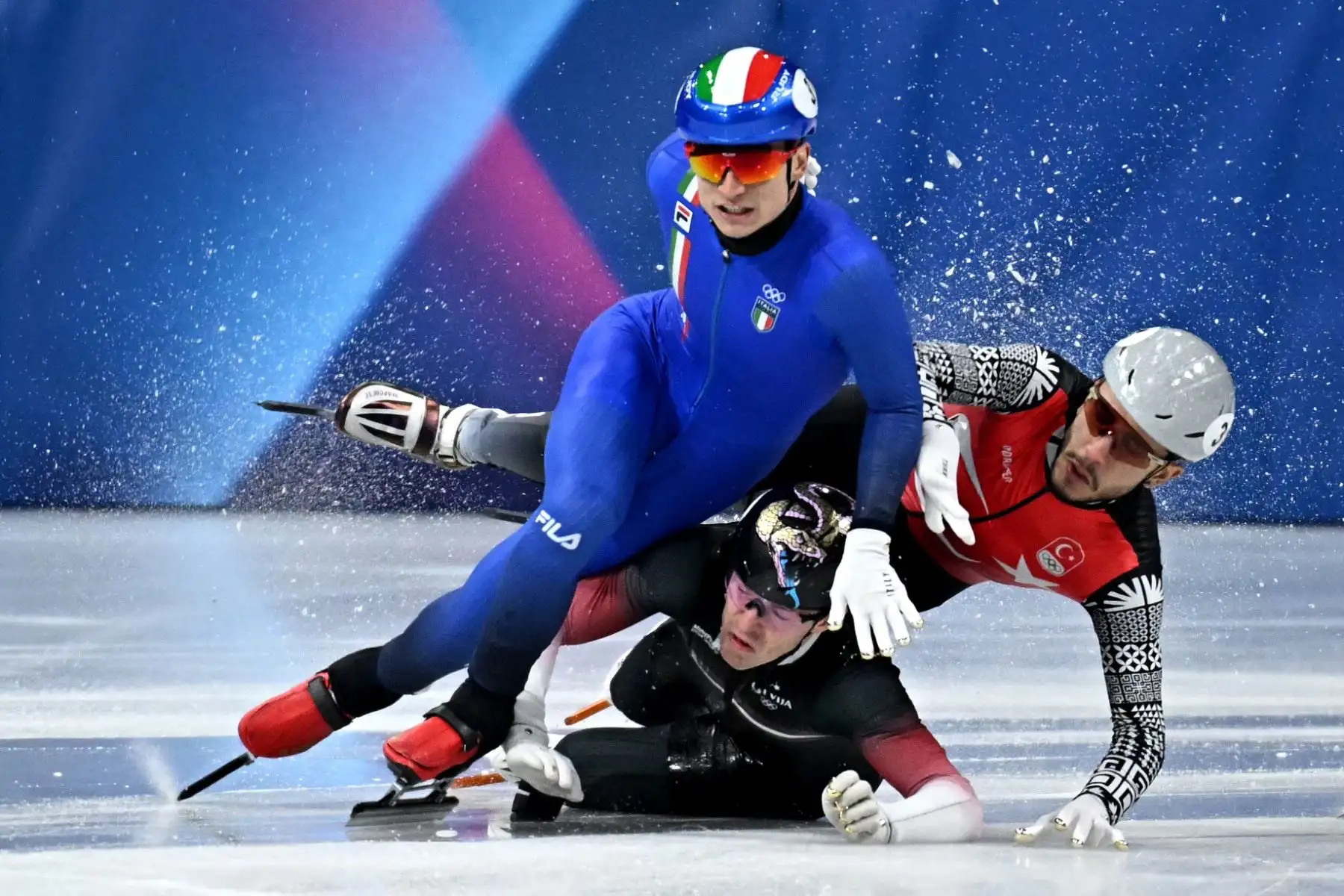 Pietro Sighel de Italia, Reinis Berzins de Letonia y Furkan Akar de Turquía se estrellan durante las series de 500 m masculino de patinaje de velocidad en pista corta durante los Juegos Olímpicos de Invierno Milano Cortina 2026 en el Milano Ice Skating Arena de Milán. Foto: AFP