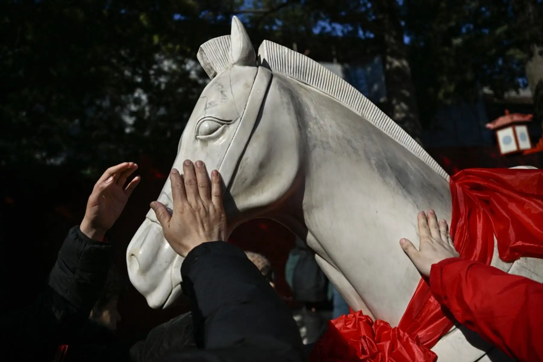 La gente toca una estatua de caballo para tener buena suerte en un templo el primer día del Año Nuevo Lunar del Caballo en Beijing. Foto: AFP
