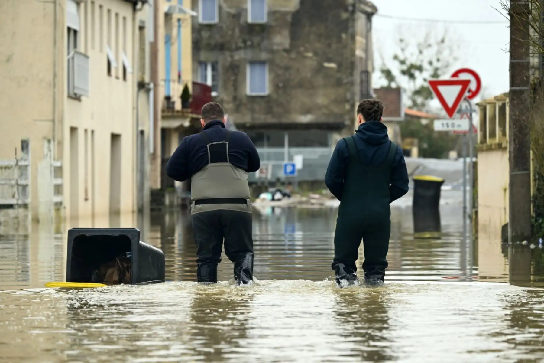 Empleados municipales caminan por el río Garona desbordado, inundando una carretera en La Reole, suroeste de Francia. Foto: AFP