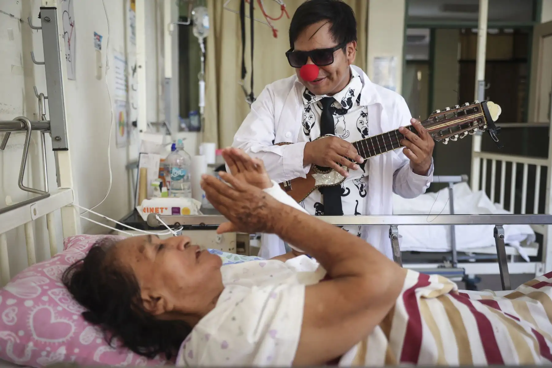 El sonido de un charango irrumpe en uno de los pasillos del hospital Cayetano Heredia y rompe, por unos segundos, la rutina marcada por pasos apurados y conversaciones en voz baja. Algunos médicos se miran sorprendidos, mientras una paciente escucha alegremente la melodía de uno de los clown que ha llegado a visitarla. Foto: ANDINA/Jhonel Rodríguez Robles