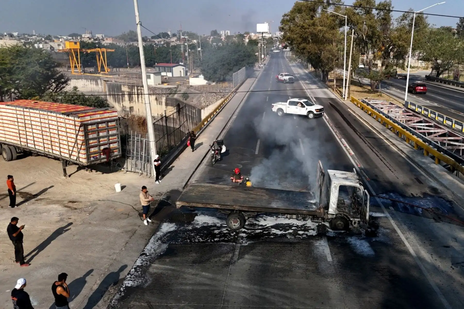 Un hombre extingue un camión en llamas, incendiado por grupos del crimen organizado en respuesta a un operativo en Jalisco para detener a un objetivo de seguridad de alta prioridad, en una de las principales avenidas de Zapopan, Jalisco, México, el 22 de febrero de 2026. Foto: AFP