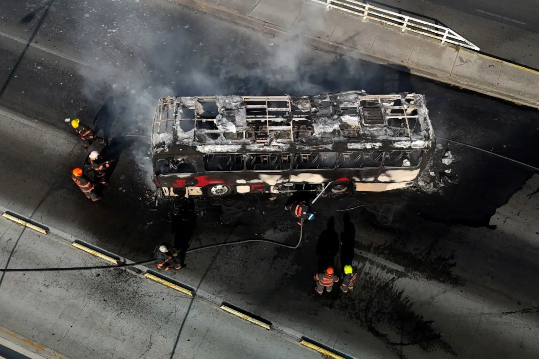 En esta vista aérea, bomberos extinguen un autobús en llamas, incendiado por grupos del crimen organizado en respuesta a un operativo en Jalisco para detener a un objetivo de seguridad de alta prioridad, en una de las principales avenidas de Zapopan, estado de Jalisco, México, el 22 de febrero de 2026. Foto: AFP