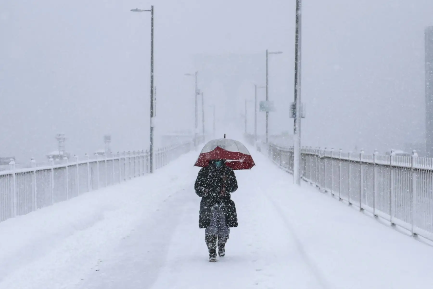 Una persona cruza el puente de Brooklyn durante una tormenta invernal en la ciudad de Nueva York el 23 de febrero de 2026. Nueva York ordenó a los conductores que se fueran de la carretera y cerraron las escuelas el lunes. Foto: AFP