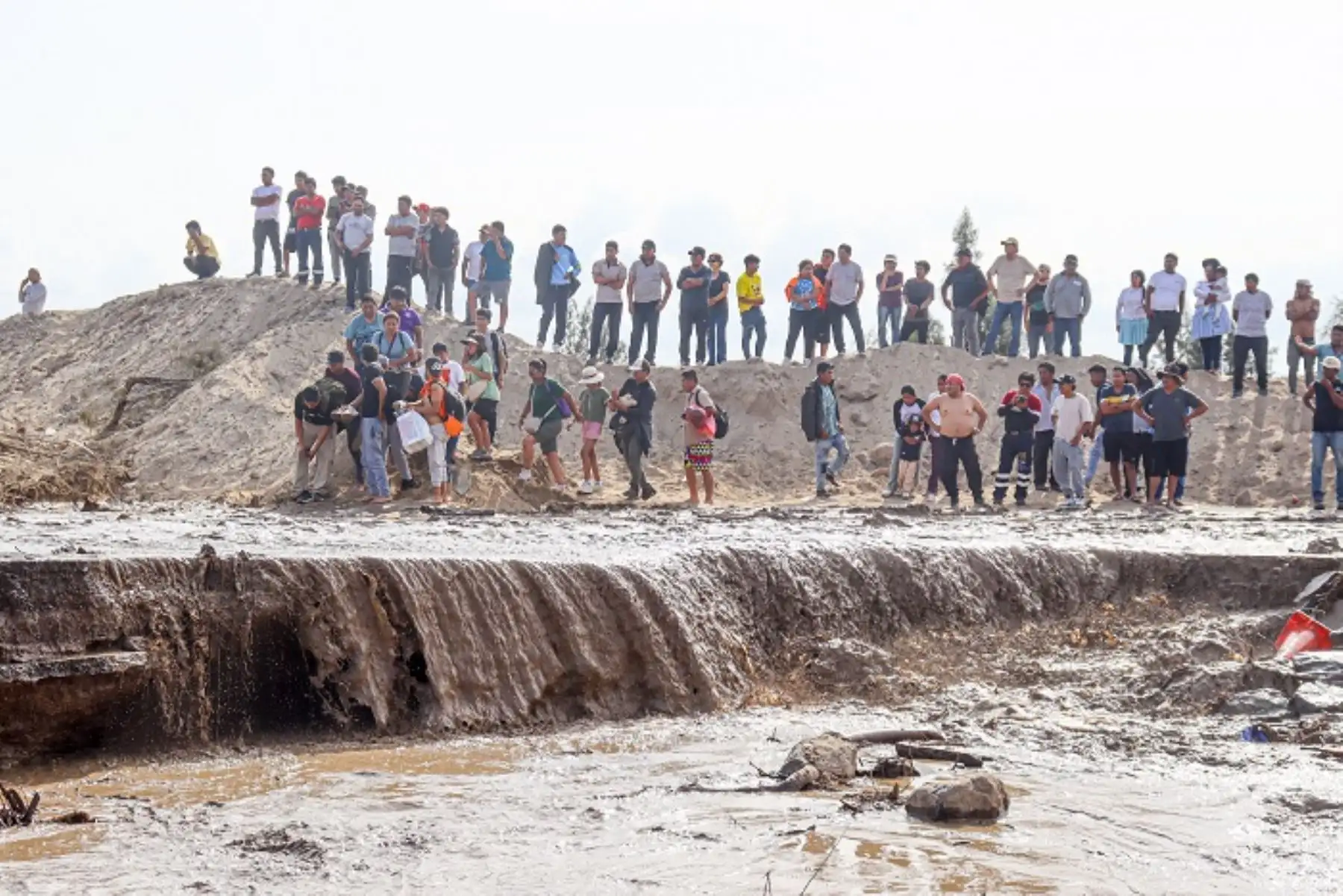 Ante la desesperación, cientos de personas han optado por arriesgar su integridad física cruzando a pie el cauce del huaico para realizar transbordos y llegar a sus destinos.