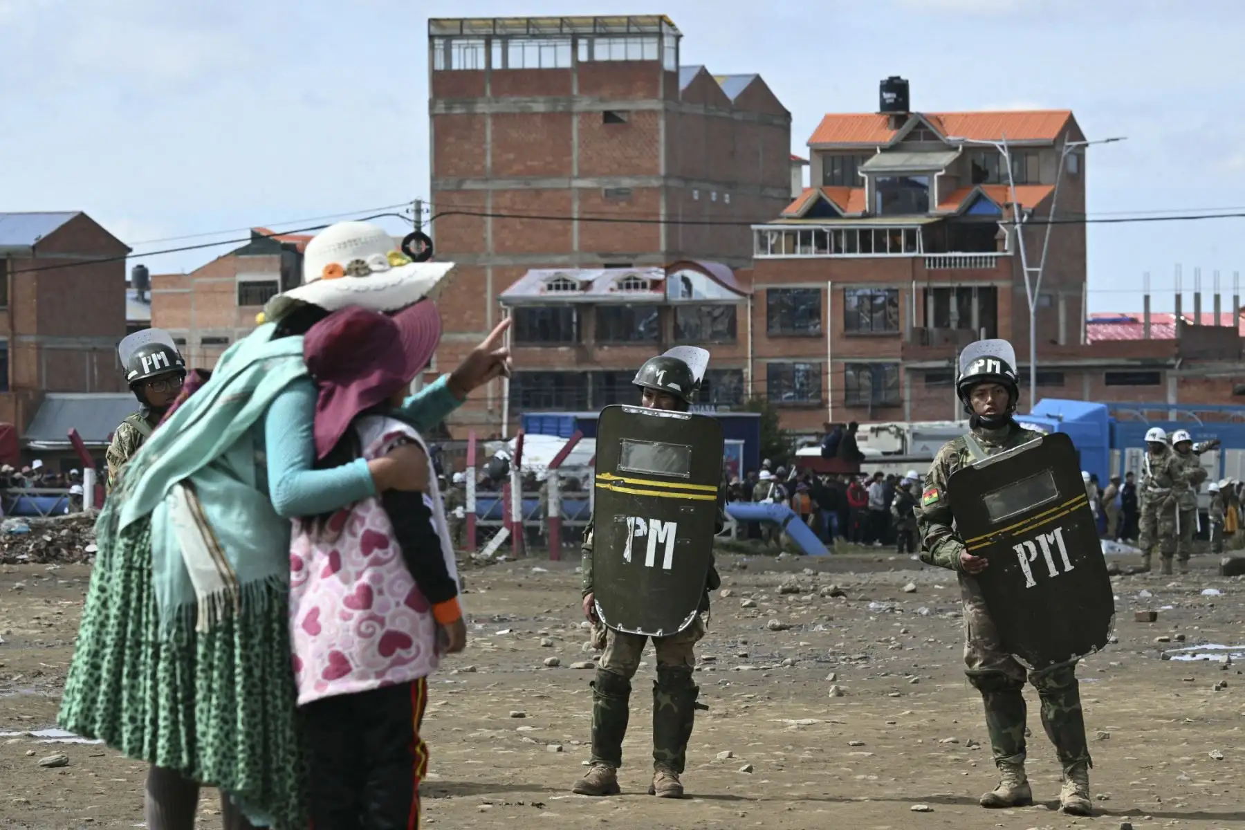 Los oficiales de la policía militar boliviano están de guardia mientras las personas llegan al lugar del accidente del avión Lockheed C-130 de la Fuerza Aérea Boliviana (FAB-81) en El Alto, cerca de La Paz, el 28 de febrero de 2026. Al menos 20 personas murieron el 27 de febrero en un accidente aéreo militar en Bolivia que transportaba efectivo y se estrellaron mientras aterrizaba en el aeropuerto de El Alto, cerca de La Paz, informaron las autoridades. (Foto de AIZAR RALDES / AFP