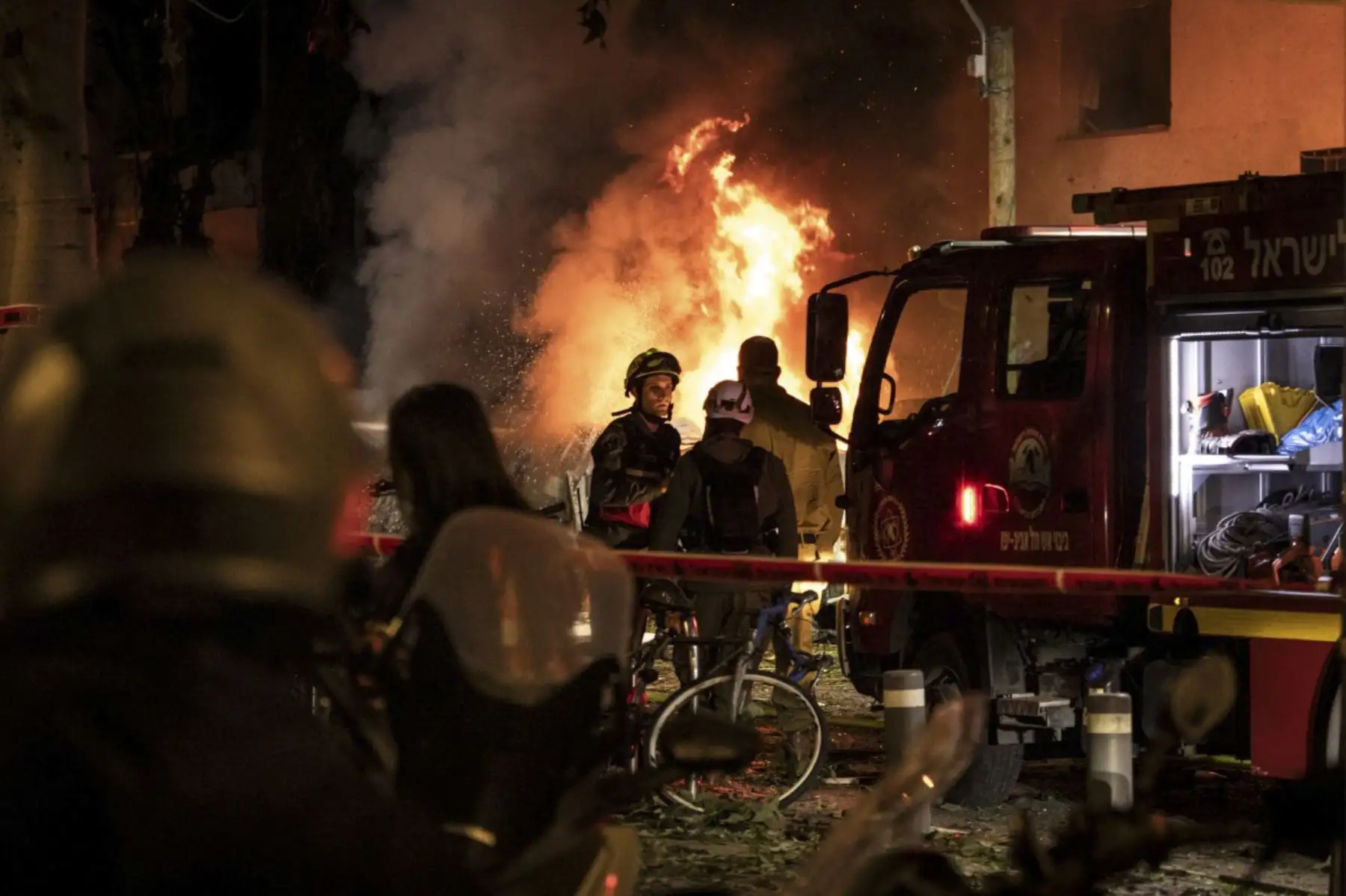 Se ve a los bomberos de pie frente a un incendio en el lugar de un ataque con misiles iraníes en Tel Aviv el 28 de febrero de 2026. Estados Unidos e Israel lanzaron ataques contra Irán el 28 de febrero, y la emisora pública de Israel informó que el líder supremo iraní había sido atacado, ya que la República Islámica tomó represalias con aluvión de misiles contra los estados del Golfo e Israel. (Foto de JOHN WESSELS / AFP)