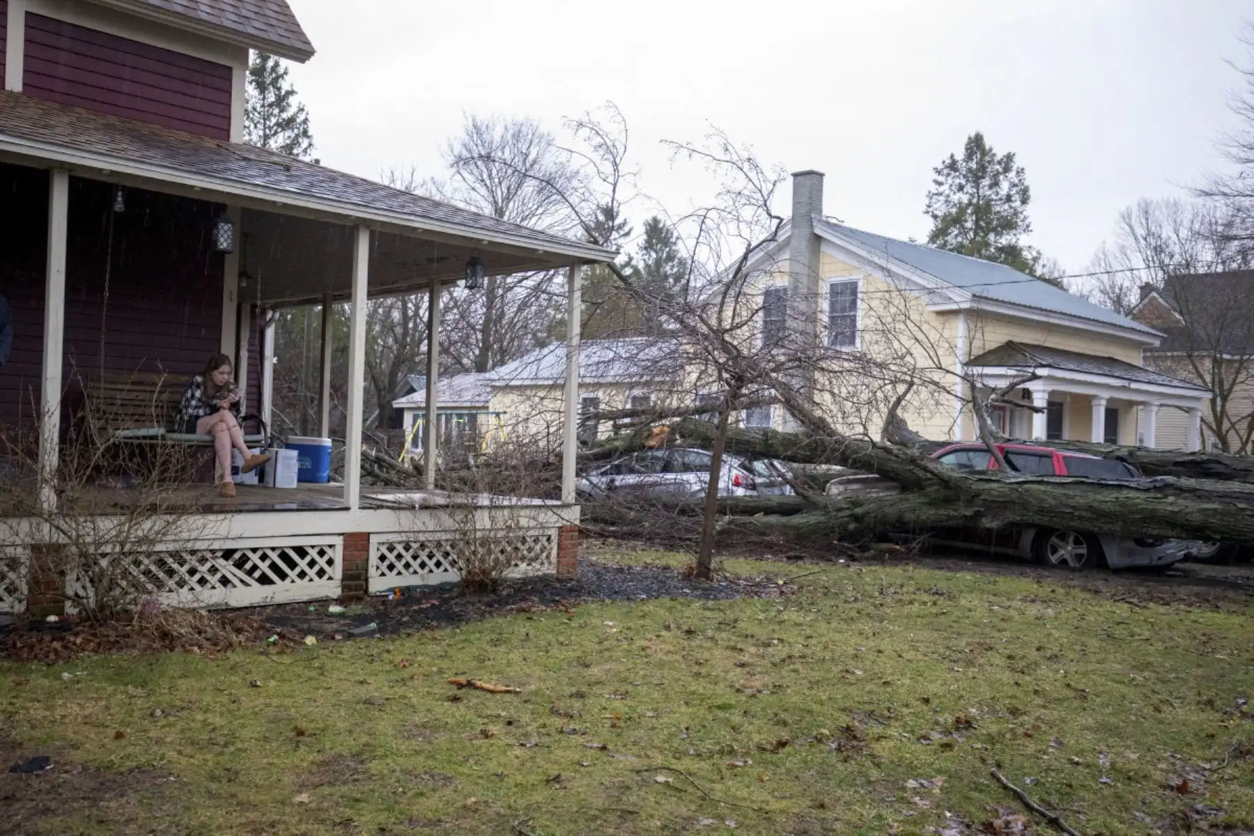 La residente Kara Klein se sienta en el porche delantero de su casa, donde el SUV Chevy Trailblazer y el Ford Fiesta de su familia fueron aplastados por un árbol que cayó y que fue arrancado por un tornado el 7 de marzo de 2026 en Union City, Michigan. Varias personas murieron y alrededor de una docena más resultaron heridas por la tormenta en Union City. Foto: AFP
