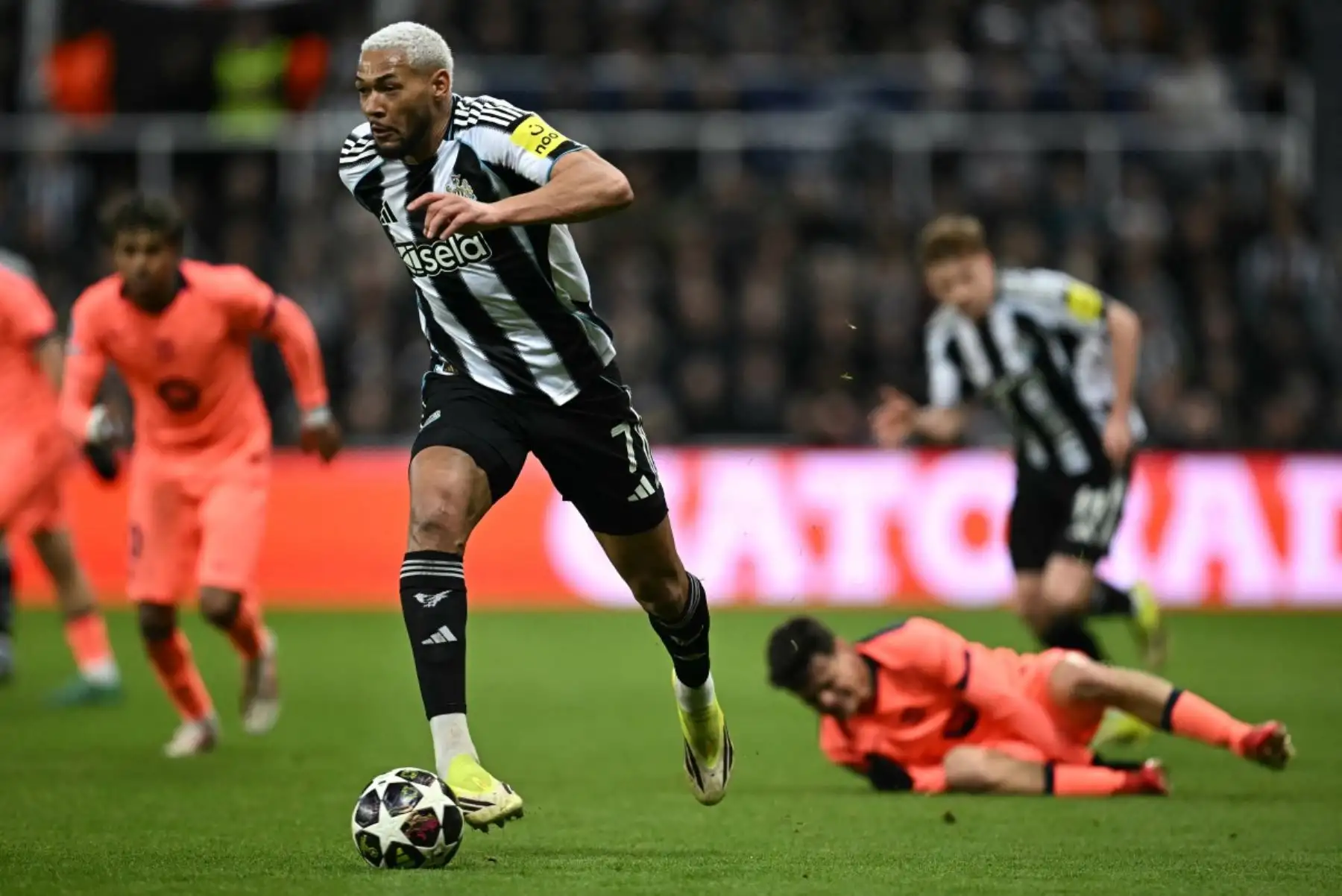 El centrocampista brasileño del Newcastle United Joelinton corre con el balón del defensa español del Barcelona  Pau Cubarsi durante el partido de octavos de final de la UEFA Champions League entre el Newcastle United y el FC Barcelona. Foto: AFP