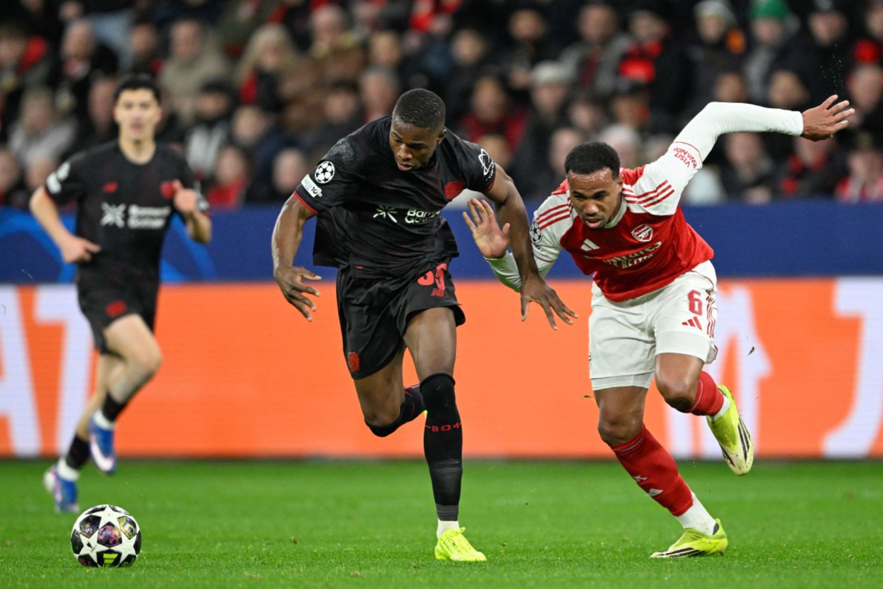 El defensa brasileño del Arsenal, Gabriel Magalhaes  y el delantero camerunés del Bayer Leverkusen, Christian Kofane, compiten por el balón durante el partido de ida de los octavos de final de la UEFA Champions League, Bayer  Leverkusen vs Arsenal. Foto: AFP