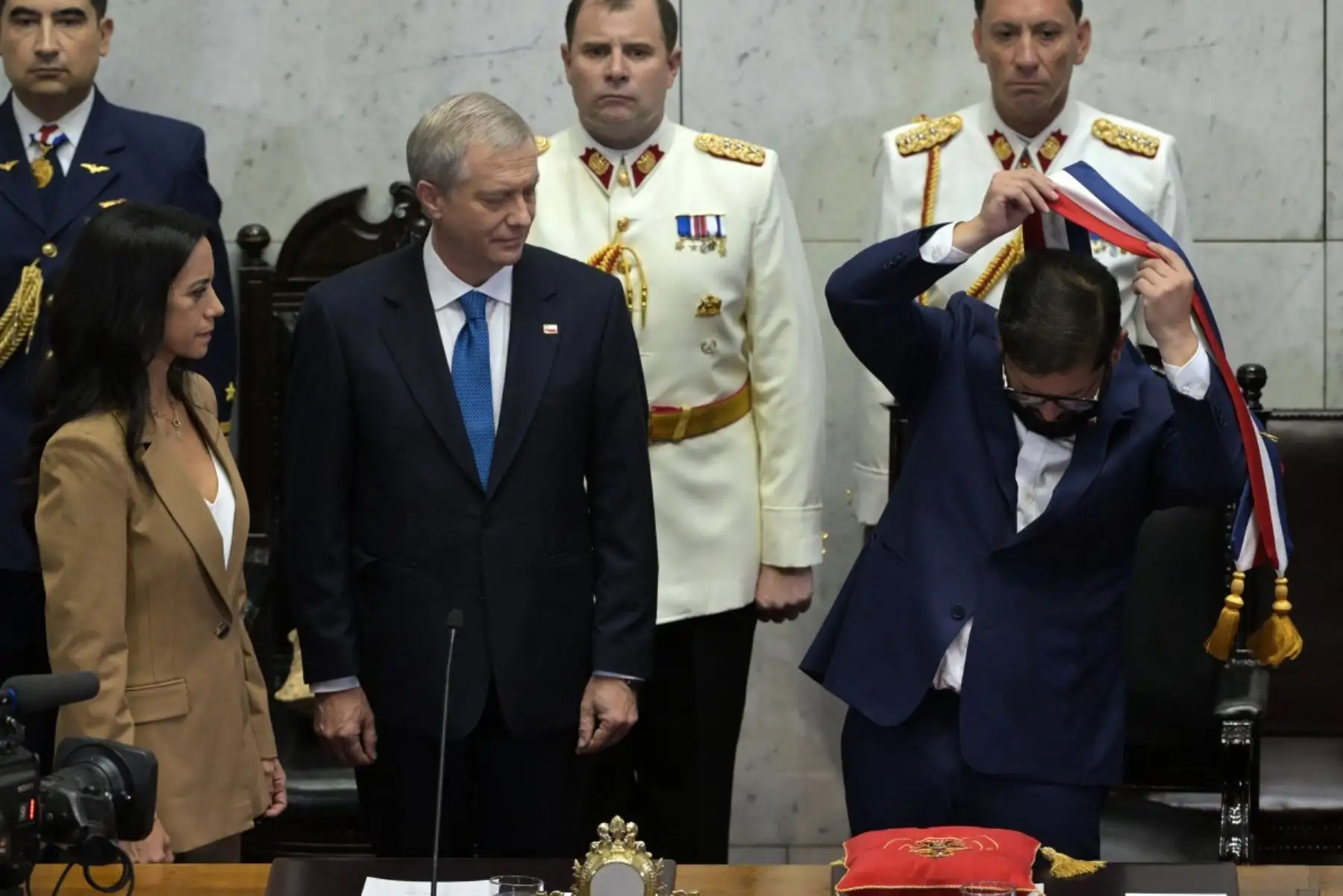 El presidente saliente de Chile, Gabriel Boric, se quita la banda presidencial junto al nuevo presidente, José Antonio Kast (centro), en el Congreso Nacional en Valparaíso, Chile. Foto: AFP