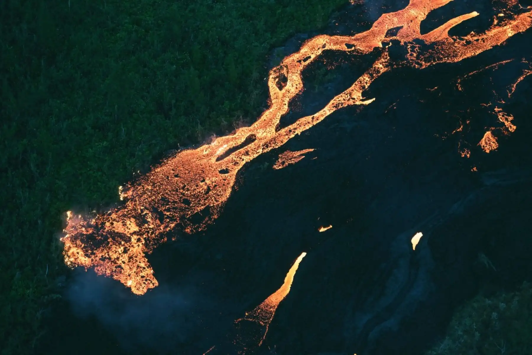 Flujo de lava abriéndose paso a través de una zona boscosa y cruzando la carretera RN2 cerca de Sainte-Rose, próxima al volcán Piton de la Fournaise, en el sureste de la isla francesa de La Reunión. Foto: AFP