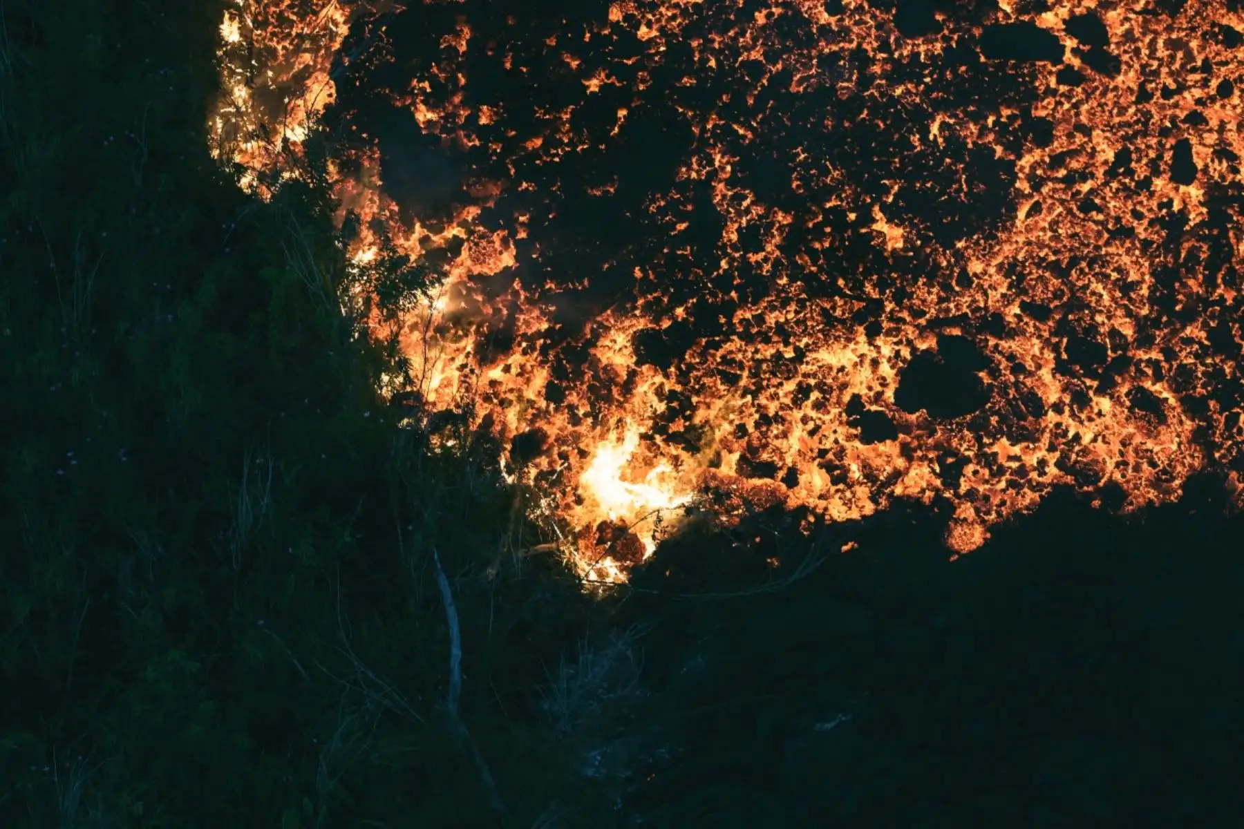 Flujo de lava abriéndose paso a través de una zona boscosa y cruzando la carretera RN2 cerca de Sainte-Rose, próxima al volcán Piton de la Fournaise, en el sureste de la isla francesa de La Reunión. Foto: AFP