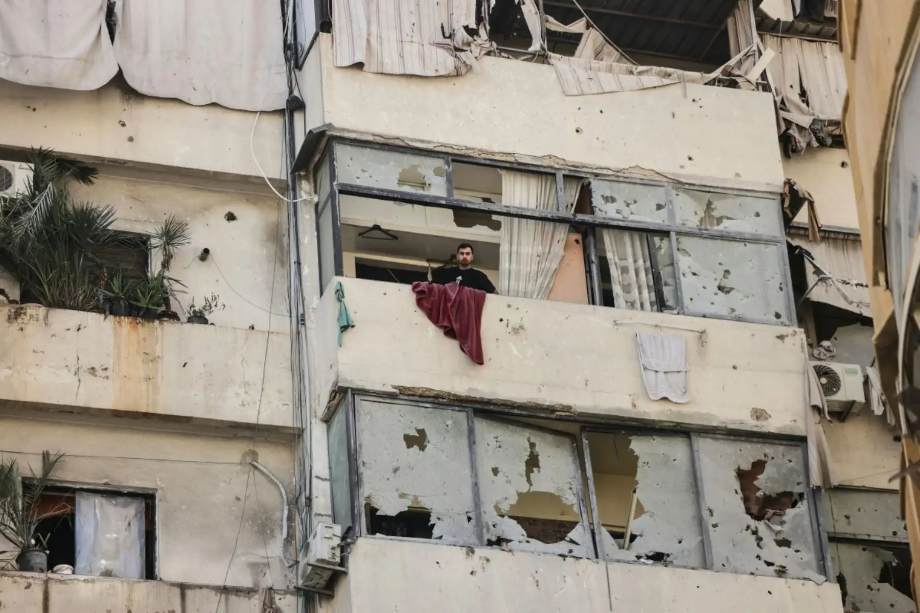 Un hombre permanece en el balcón de un edificio dañado tras un ataque aéreo israelí contra un apartamento en el barrio de Zuqaq al-Blat, en el centro de Beirut. Foto: AFP