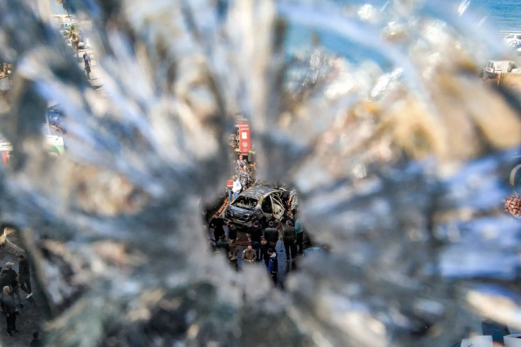 Miembros de la defensa civil se congregan alrededor de un vehículo destruido que fue blanco de un bombardeo israelí en la ciudad costera de Sidón, al sur del Líbano. Foto: AFP