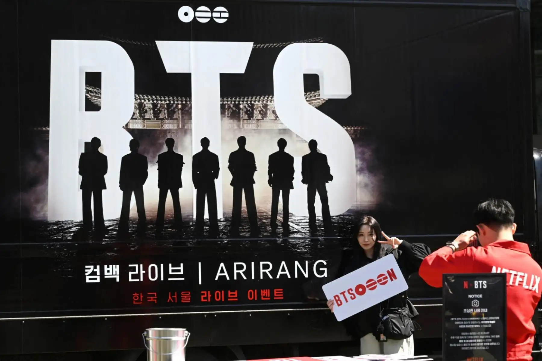 Una mujer posa para una foto frente a un camión que promociona el concierto de regreso del grupo masculino de K-pop BTS. Foto: AFP