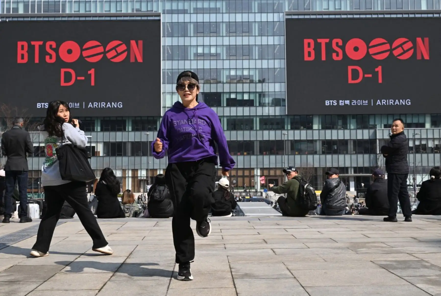 Una fan de BTS baila frente a pantallas electrónicas que promocionan el concierto de regreso del grupo de K-pop BTS en la plaza Gwanghwamun de Seúl. Foto: AFP