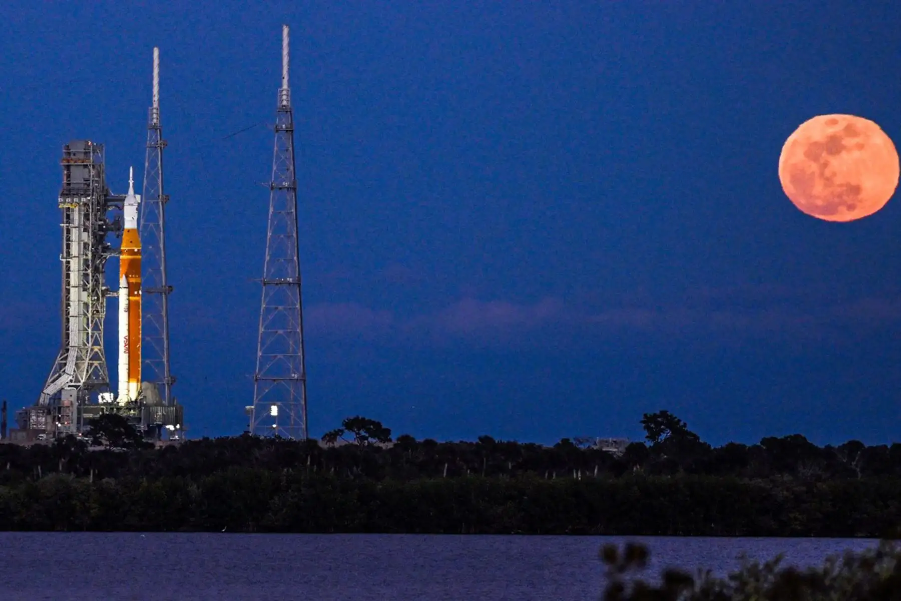 La luna llena se eleva mientras el cohete Space Launch System (SLS) y la nave espacial Orion, integrados para la misión Artemis II, se encuentran en la plataforma de lanzamiento 39B del Centro Espacial Kennedy en Cabo Cañaveral, Florida, antes de la primera misión tripulada a la Luna en más de 50 años. Foto: ANDINA/AFP
