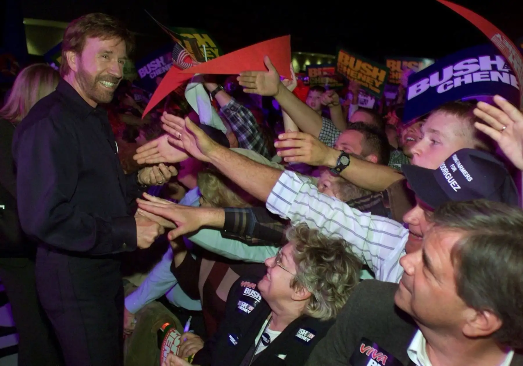 El actor Chuck Norris, estrella de la serie de televisión estadounidense "Walker, Texas Ranger", anima a la multitud en un acto de campaña a favor del candidato republicano a la presidencia de Estados Unidos y gobernador de Texas, George W. Bush. Foto: AFP