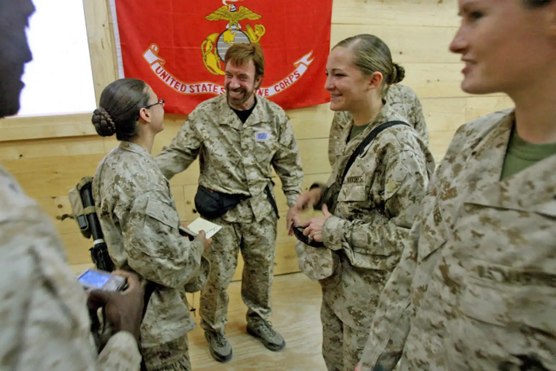 Fotografía tomada el 31 de octubre de 2006 y publicada el 1 de noviembre de 2006 por el ejército estadounidense, infantes de marina y marineros del Equipo de Combate Regimental 7, con base en California, se reúnen con la estrella de películas de acción Chuck Norris en la base aérea de Al Asad, en la provincia de Al Anbar, al oeste de Bagdad. Foto: AFP