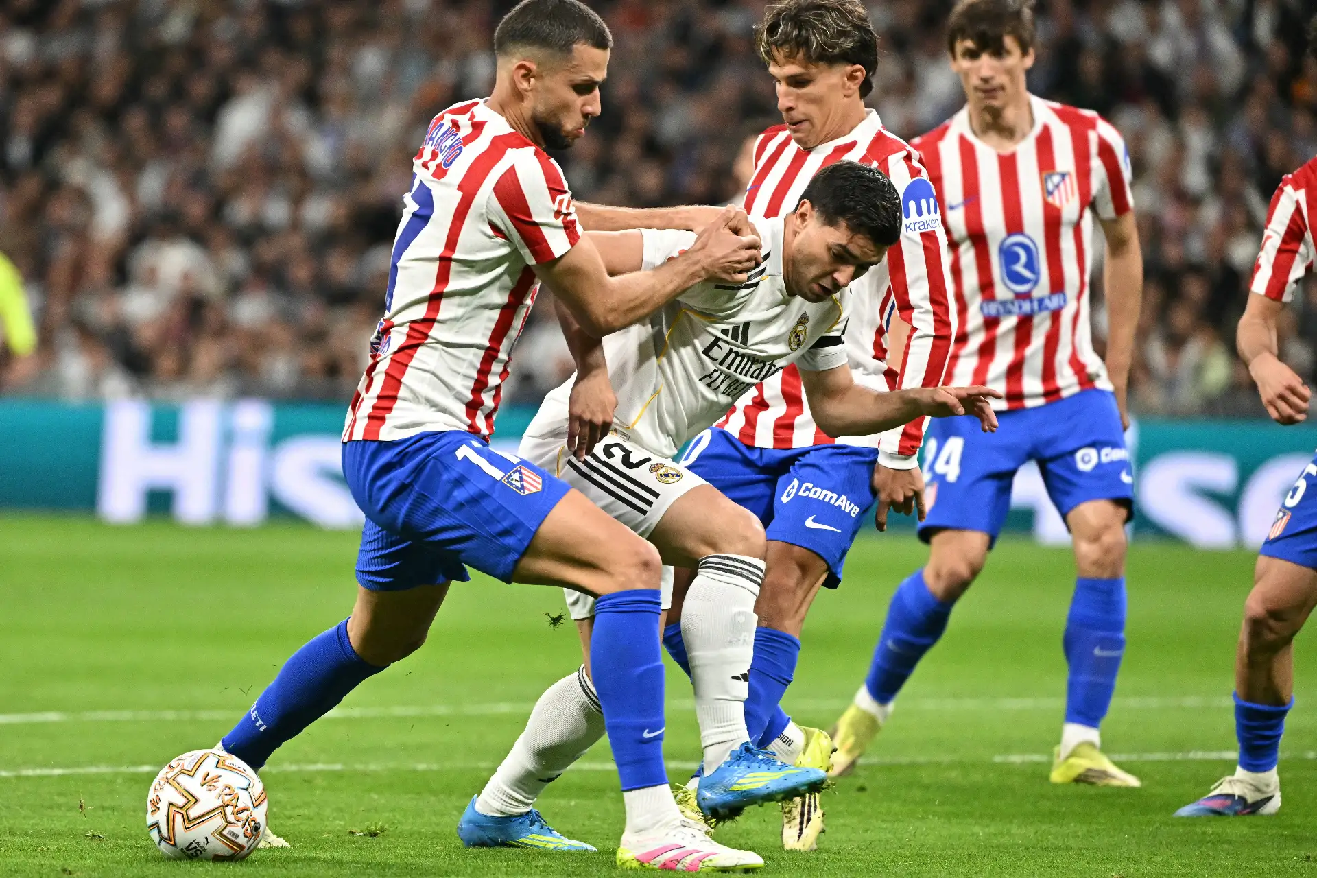 El defensa eslovaco del Atlético de Madrid, David Hancko (izq.), número 17, el delantero marroquí del Real Madrid, Brahim Díaz (segunda por la izquierda), número 21, y el delantero argentino del Atlético de Madrid, Giuliano Simeone (segunda por la izquierda), número 20, luchan por el balón durante el partido de la liga española entre el Real Madrid CF y el Club Atlético de Madrid en el estadio Santiago Bernabéu de Madrid el 22 de marzo de 2026.  Foto: AFP