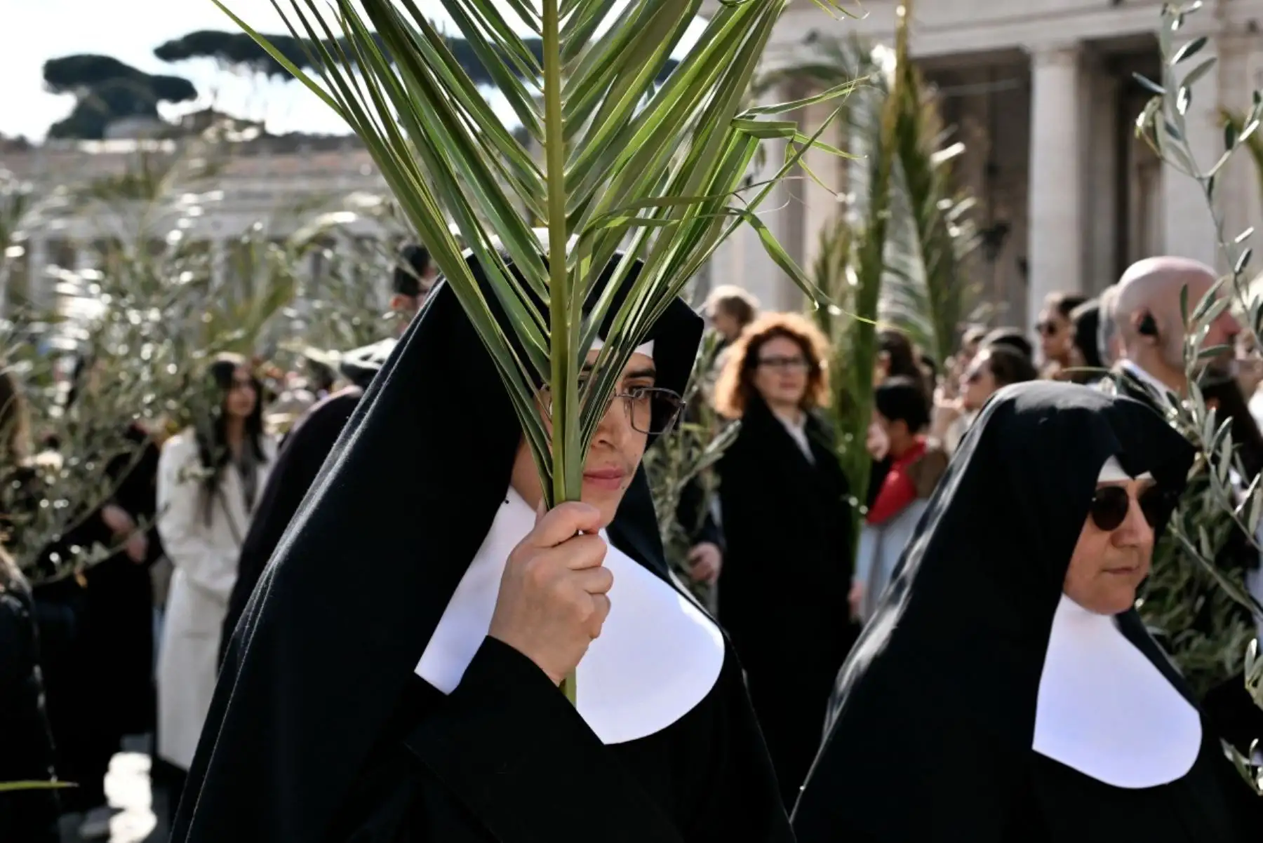 Una religiosa sostiene ramos de palma durante la procesión del Domingo de Ramos en la plaza de San Pedro, en el Vaticano, en la misa presidida por el Papa León XIV. Foto: AFP