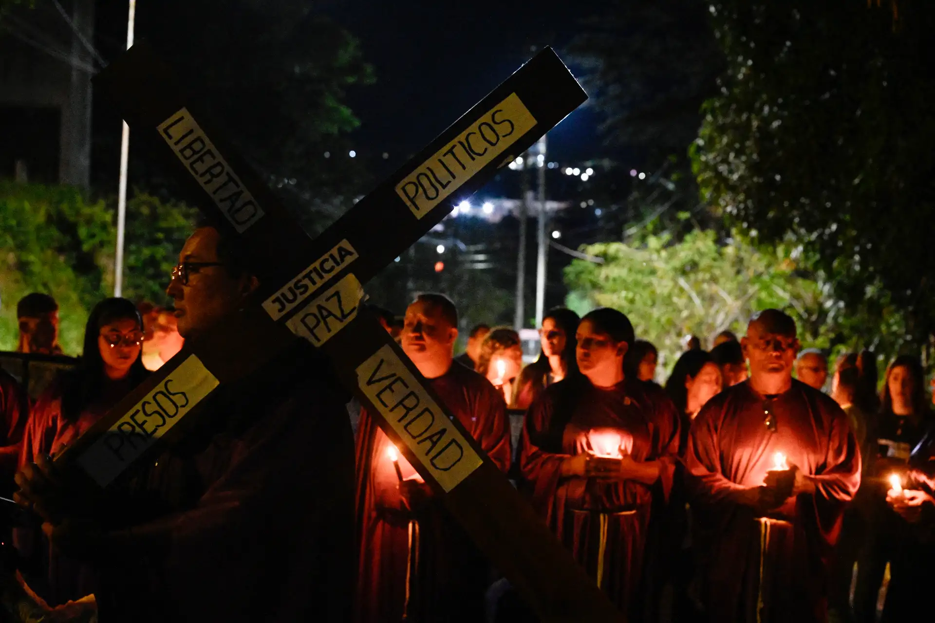 Un hombre lleva una cruz mientras participa en una procesión de fieles católicos y familiares de presos políticos a las afueras de la prisión de El Rodeo durante la Semana Santa en Guatire, estado Miranda.

Foto: AFP